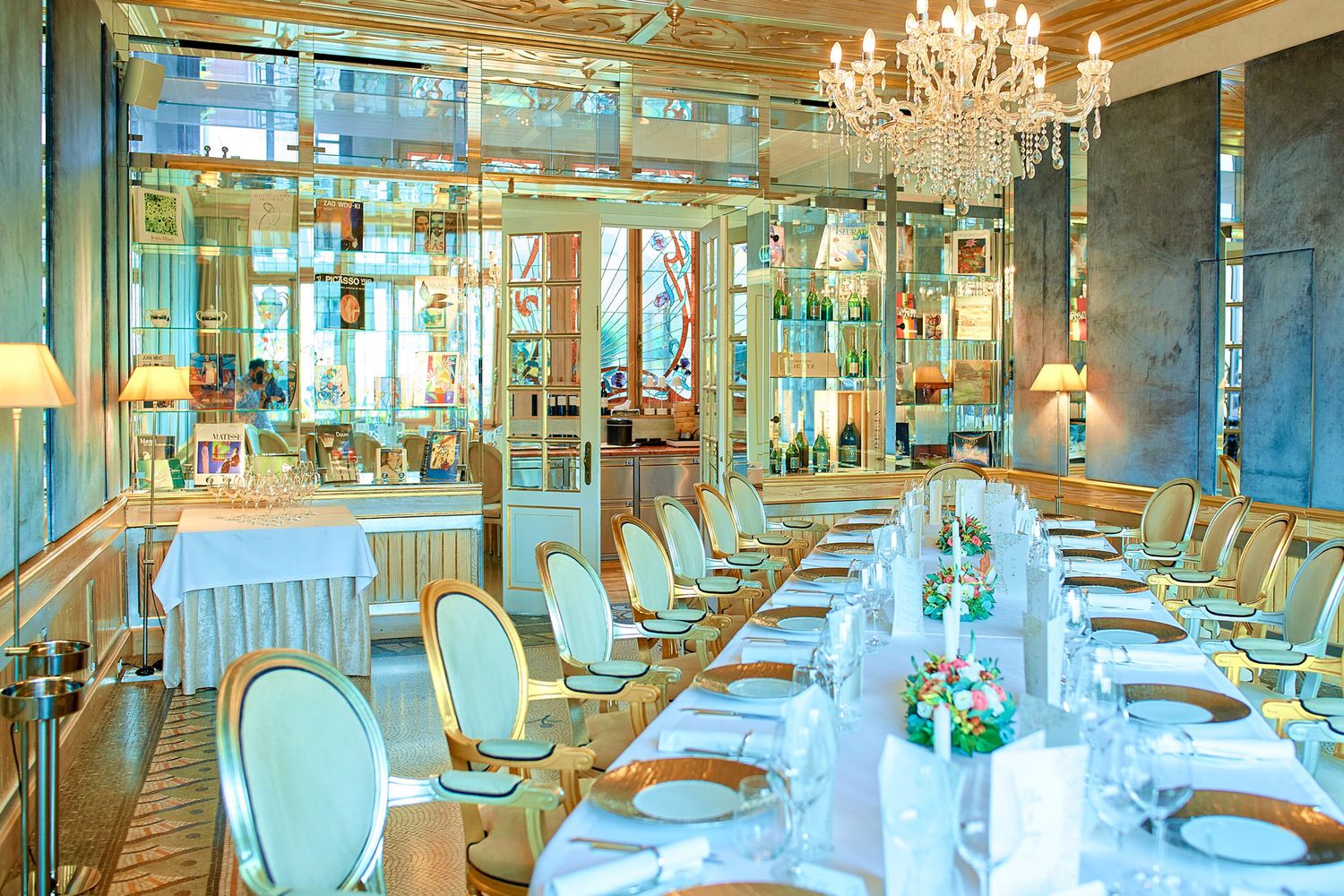 Panoramic view of an upscale restaurant dining room with crystal chandeliers and white tablecloths.