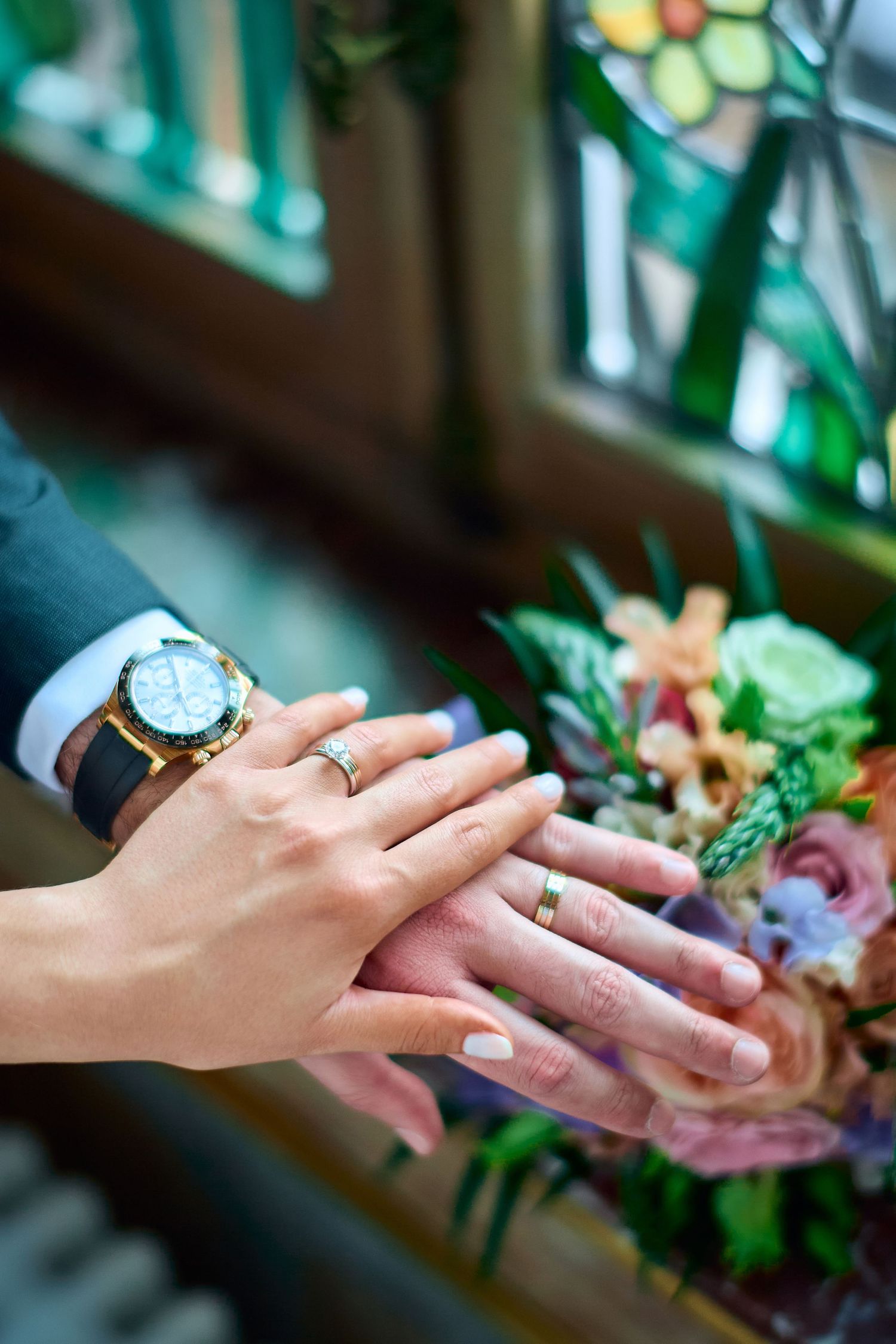 Close up of newlywed couple's hands with rings and wedding bouquet.