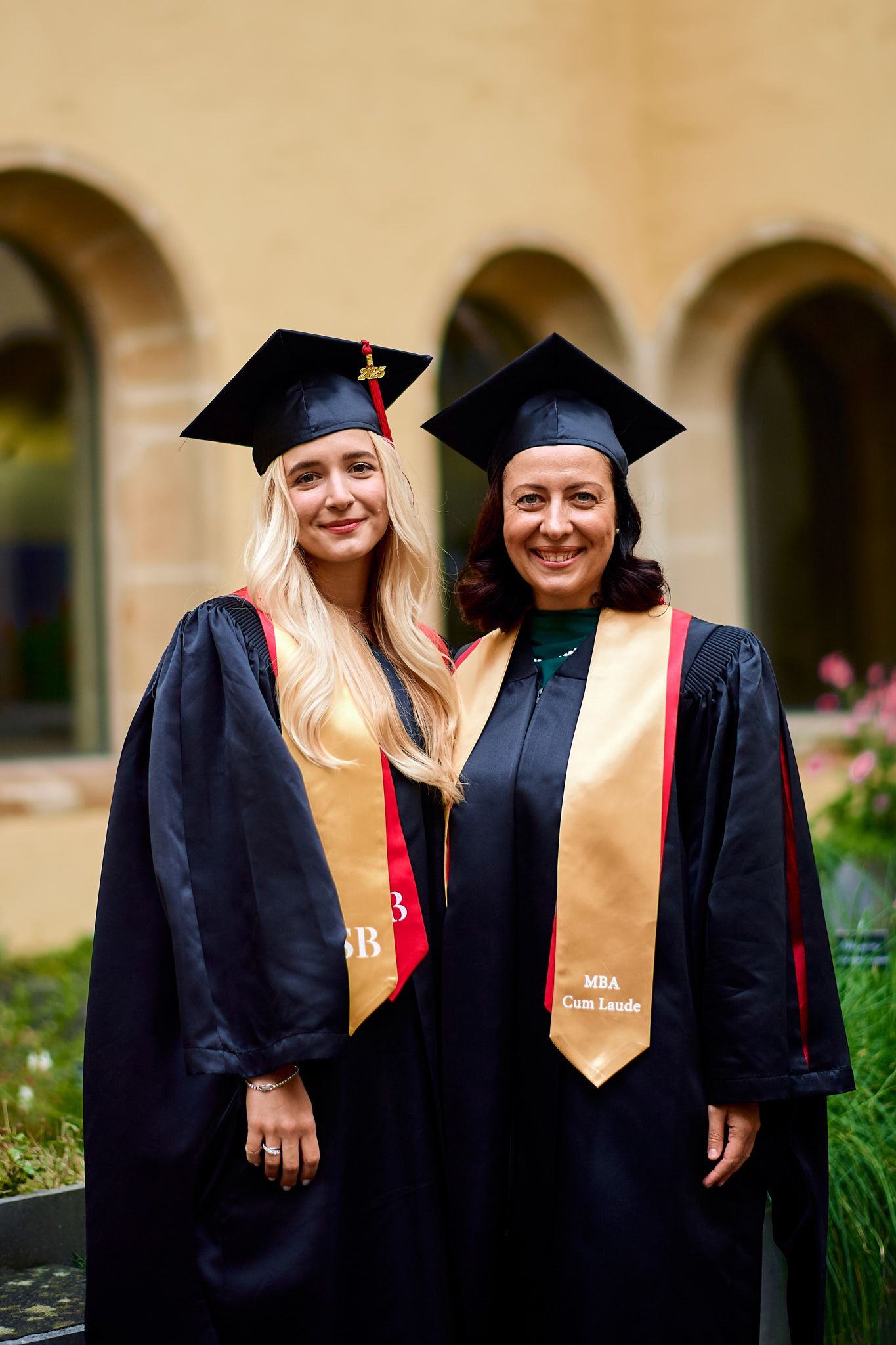 Graduates in academic regalia pose together on campus grounds.