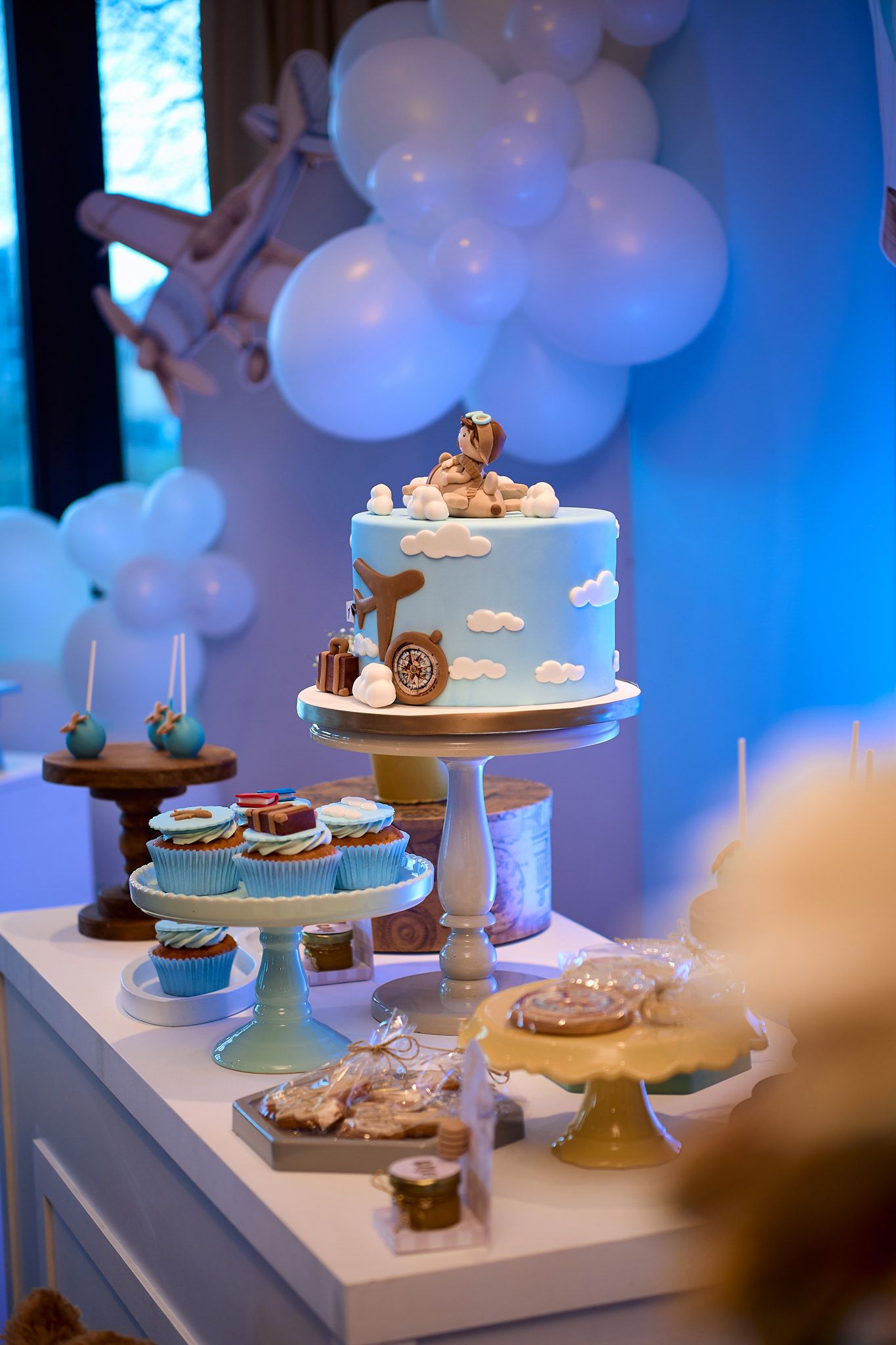 Blue and white themed dessert table with tiered cakes and cupcakes decorated for a special celebration.
