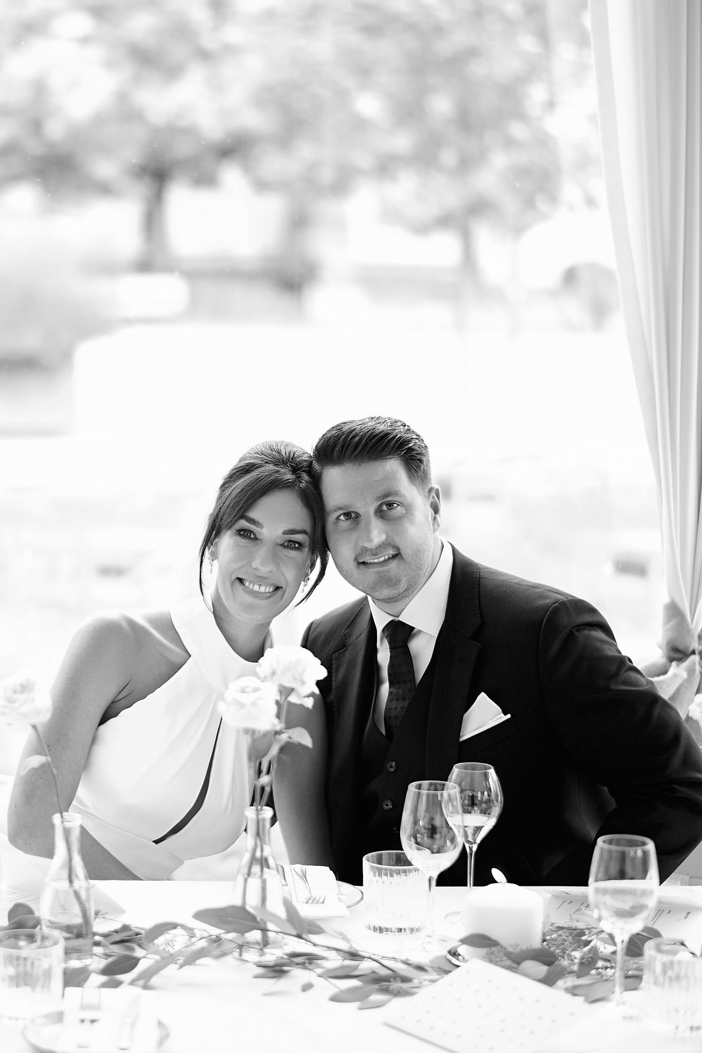 Wedding couple shares joyful moments during reception dinner under white tent.