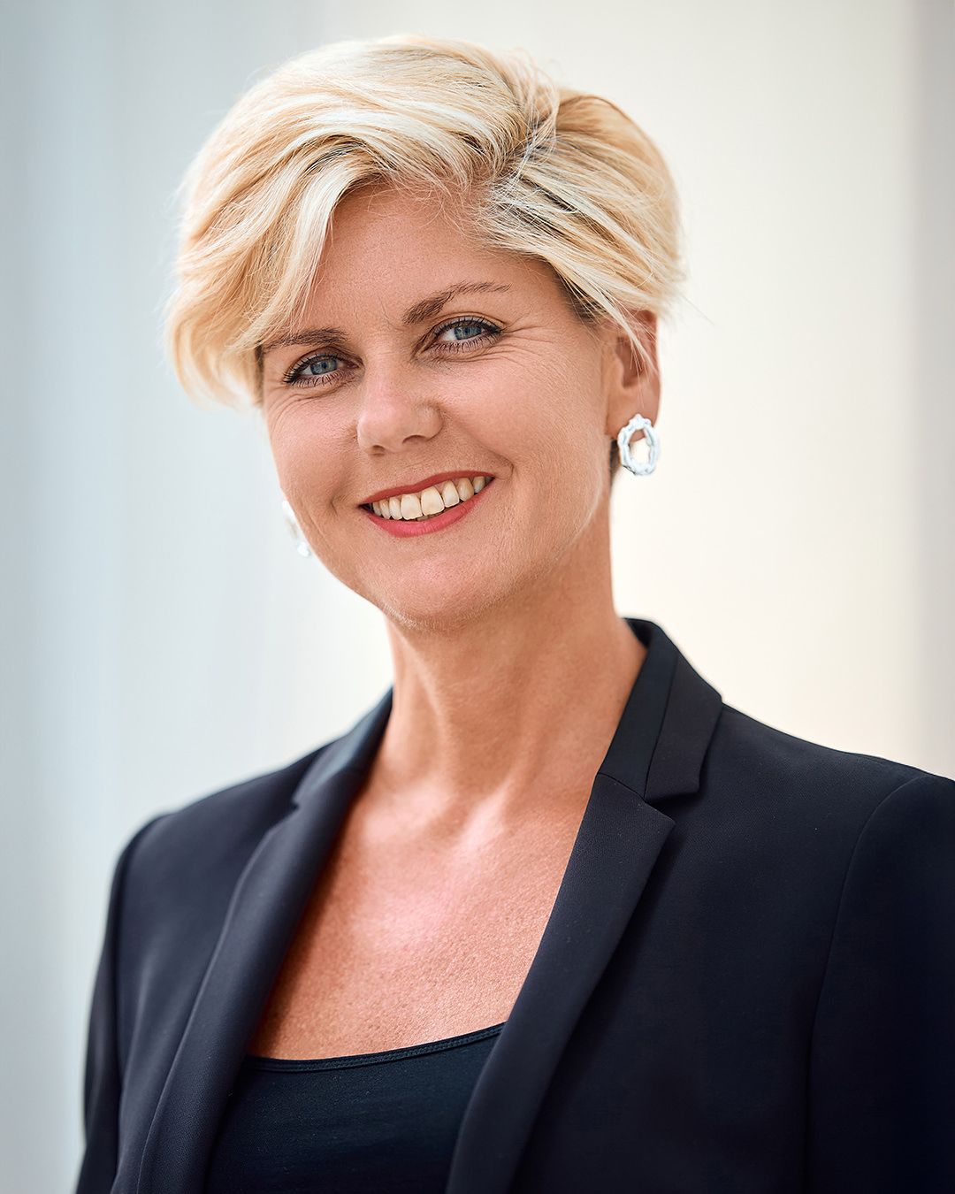 Professional headshots of a person in a black blazer against a light background.