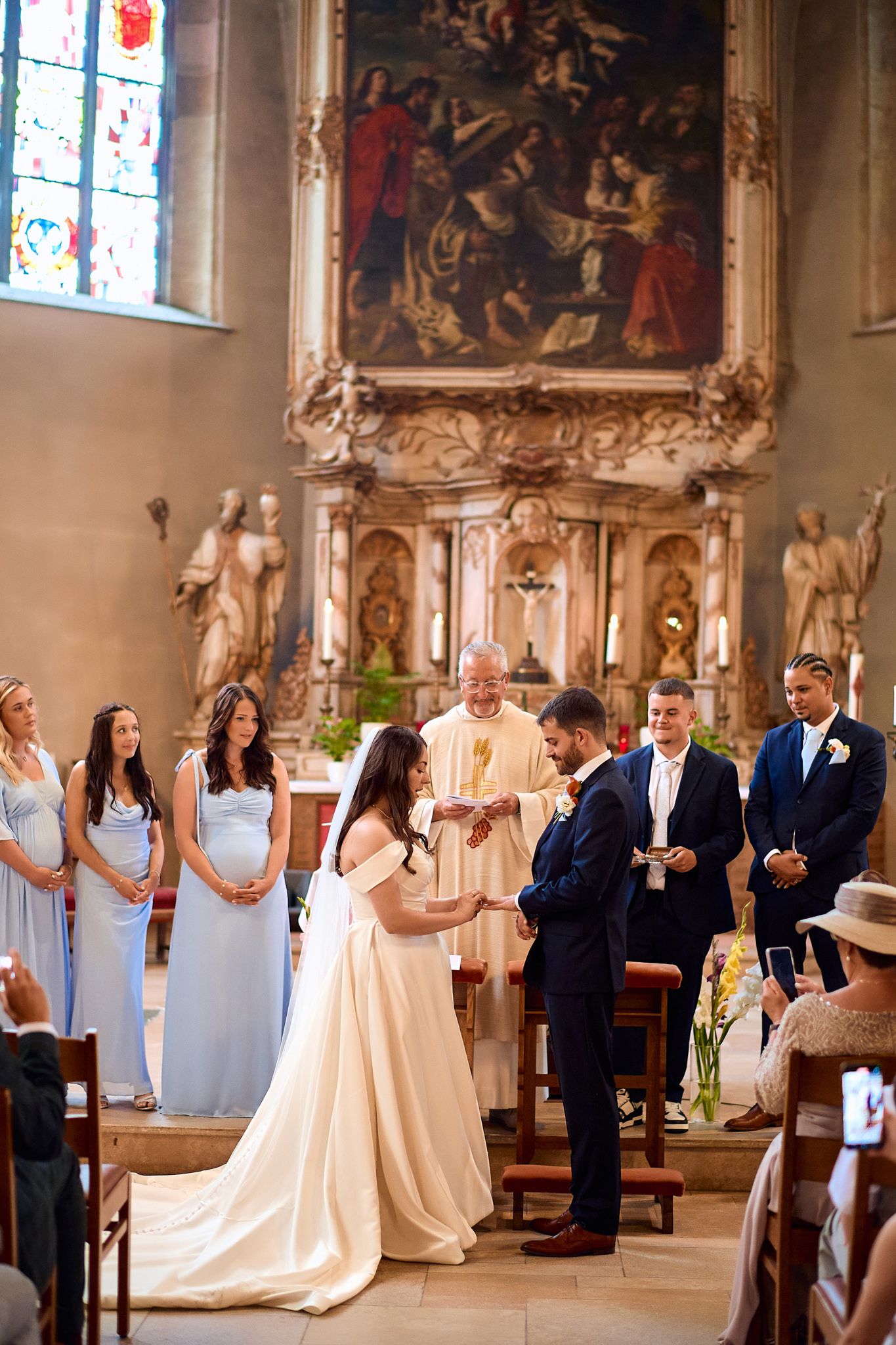 Wedding ceremony in a historic church with stained glass windows and ornate decorations.