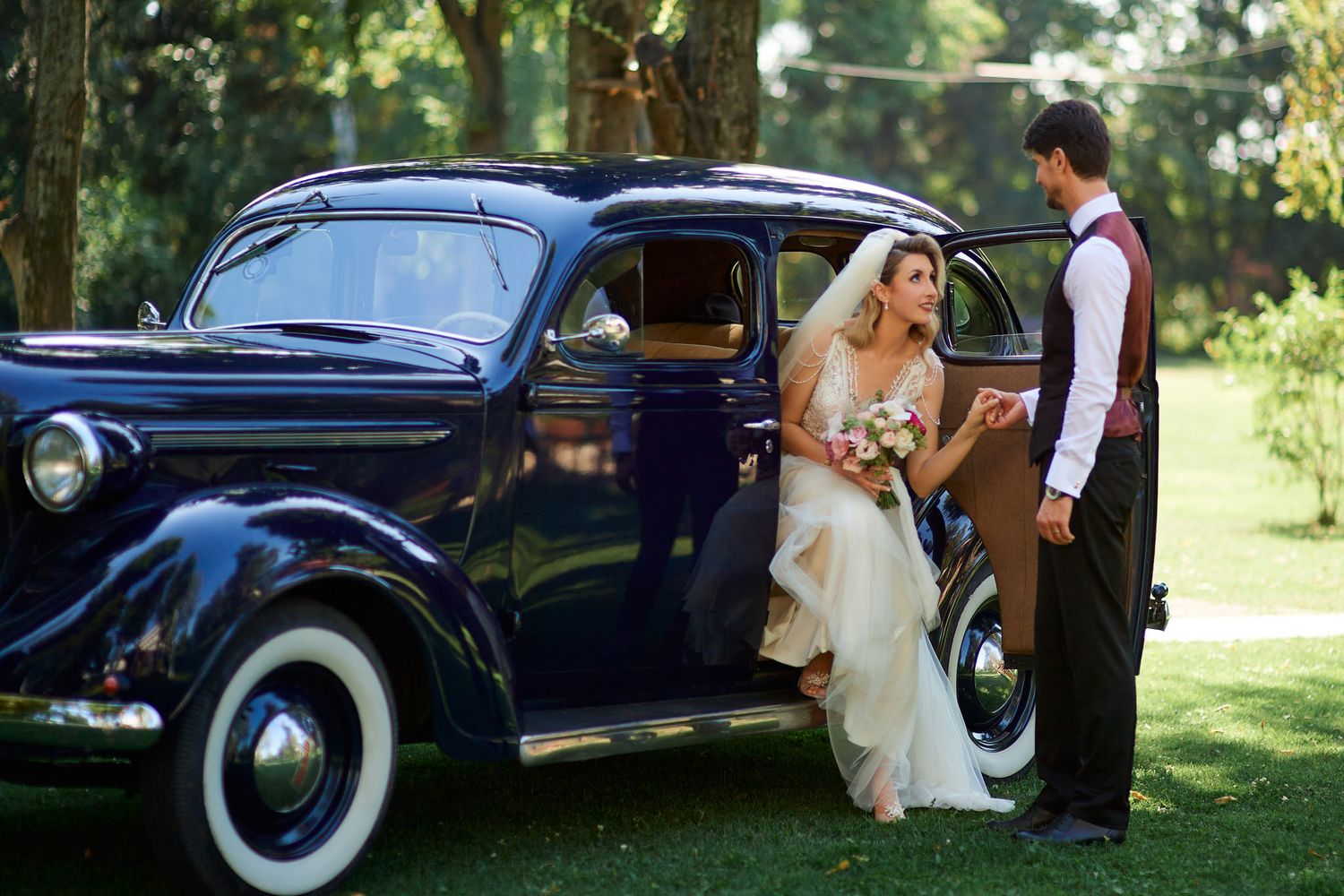 A classic dark blue vintage car photographed during a wedding event.
