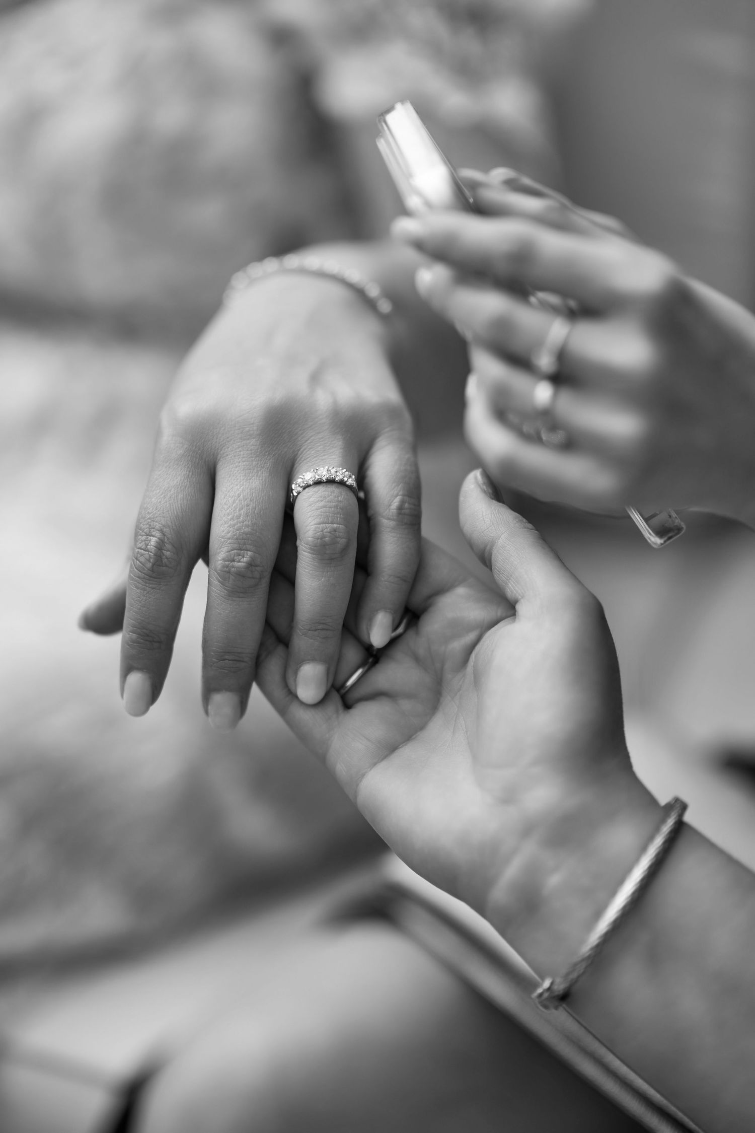 Black and white photo of hands with diamond engagement ring and bracelet, as perfume is applied.