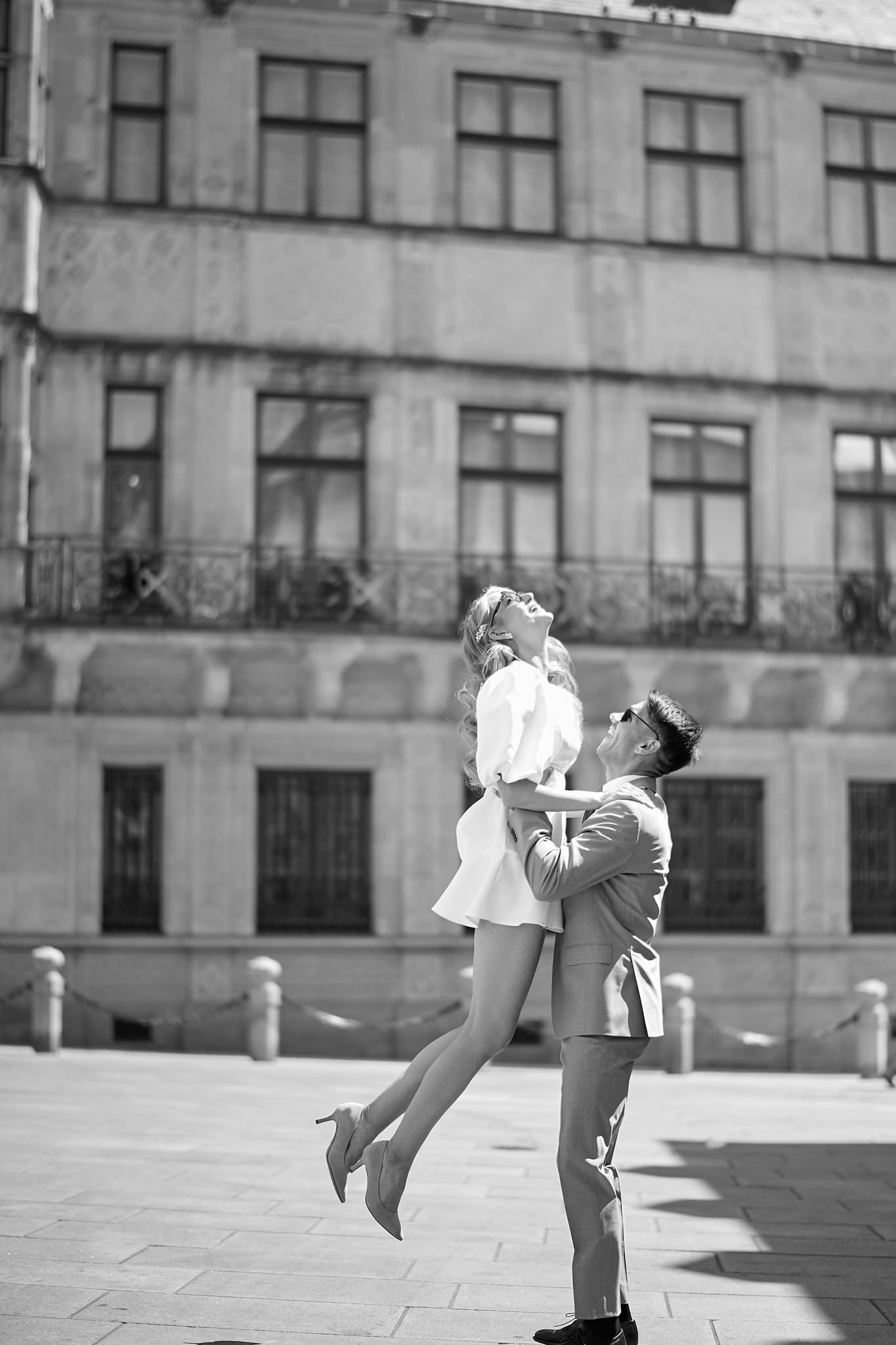 Playful black and white sequence showing a couple dancing in front of a stone building.