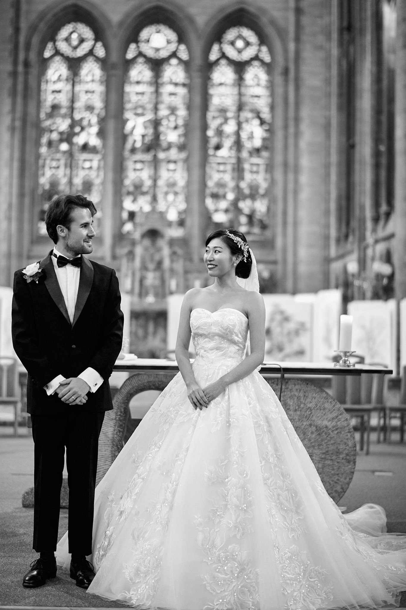 Wedding couple poses playfully in a church with ornate stained glass windows and gothic architecture.
