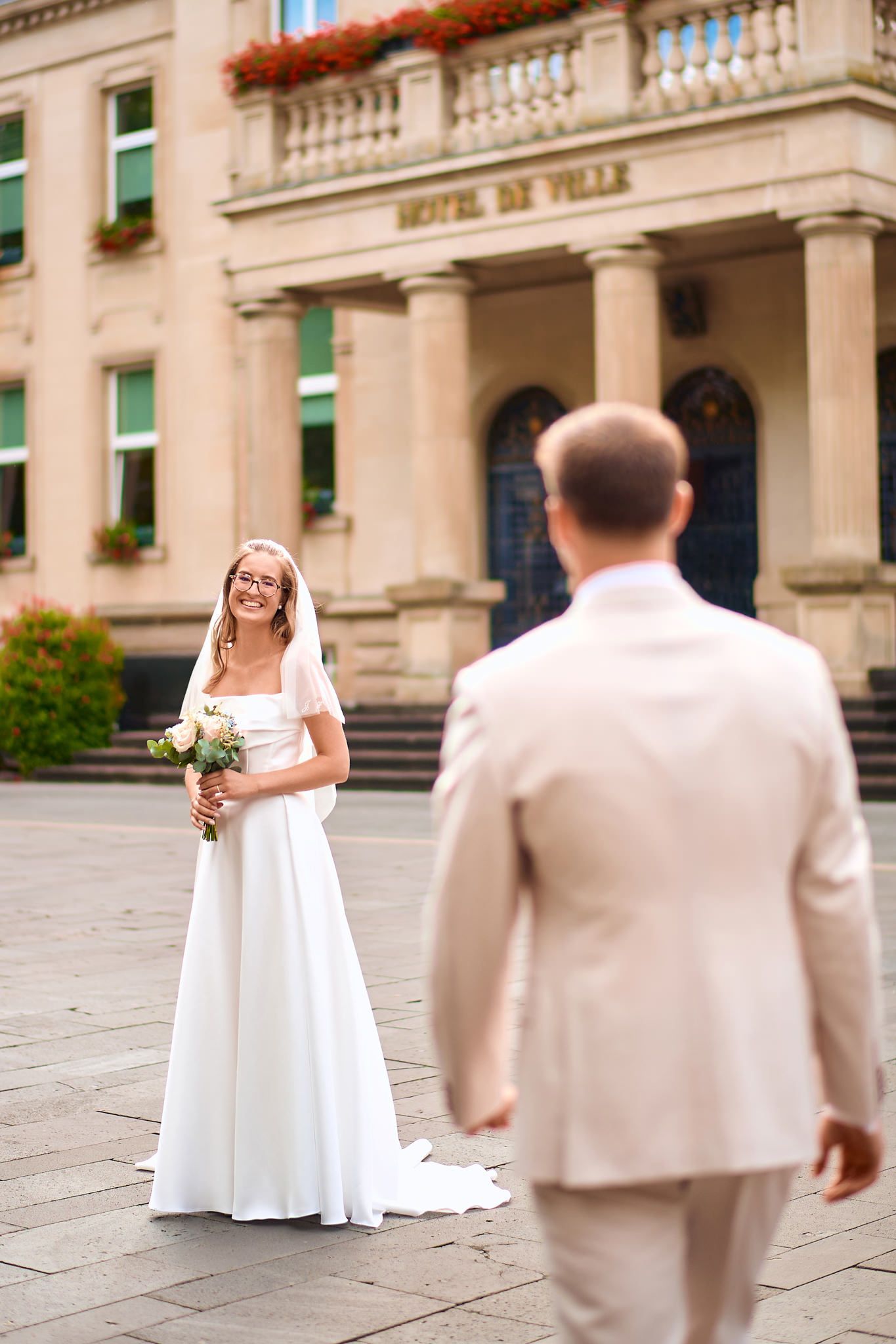 Wedding first look sequence outside a grand stone building with classical architecture.