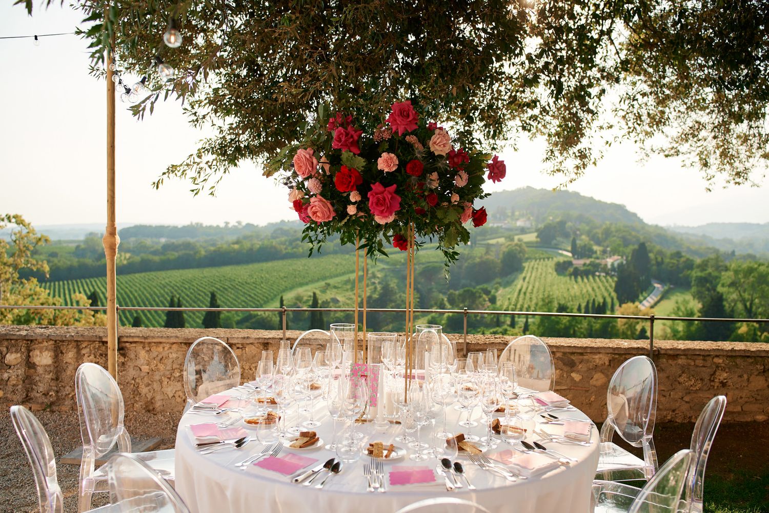Wedding reception table set with crystal glassware overlooking a scenic countryside landscape.