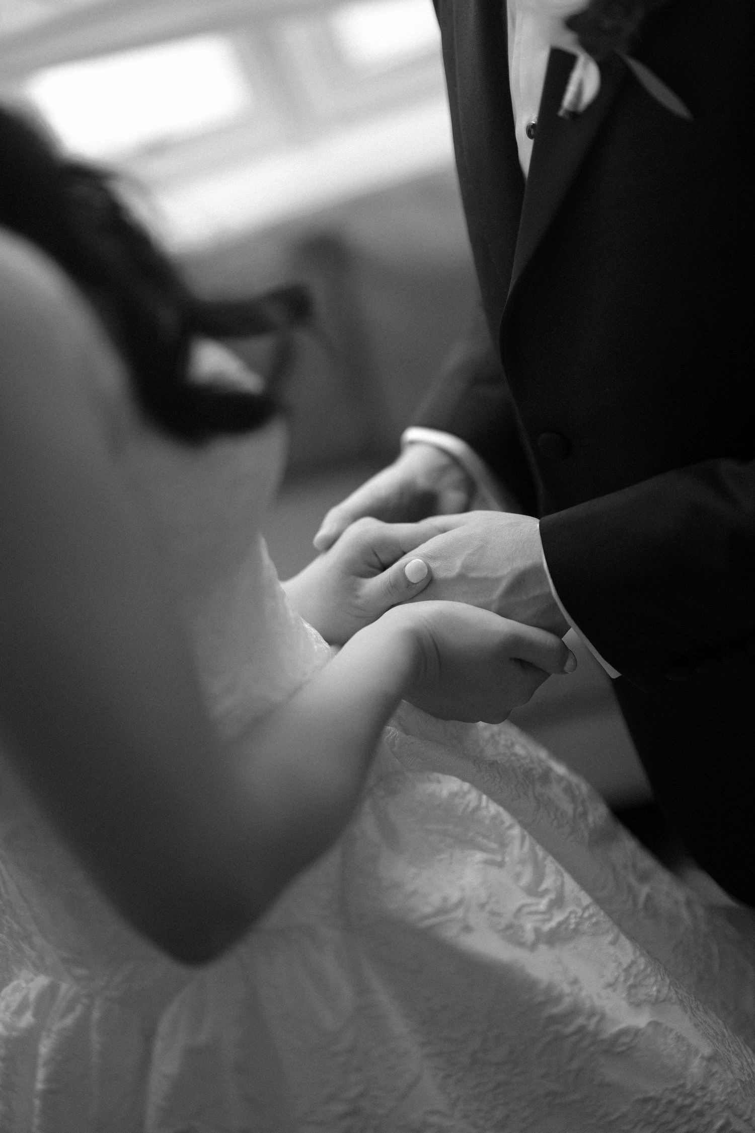 Black and white close-up of groom placing ring on bride's hand.