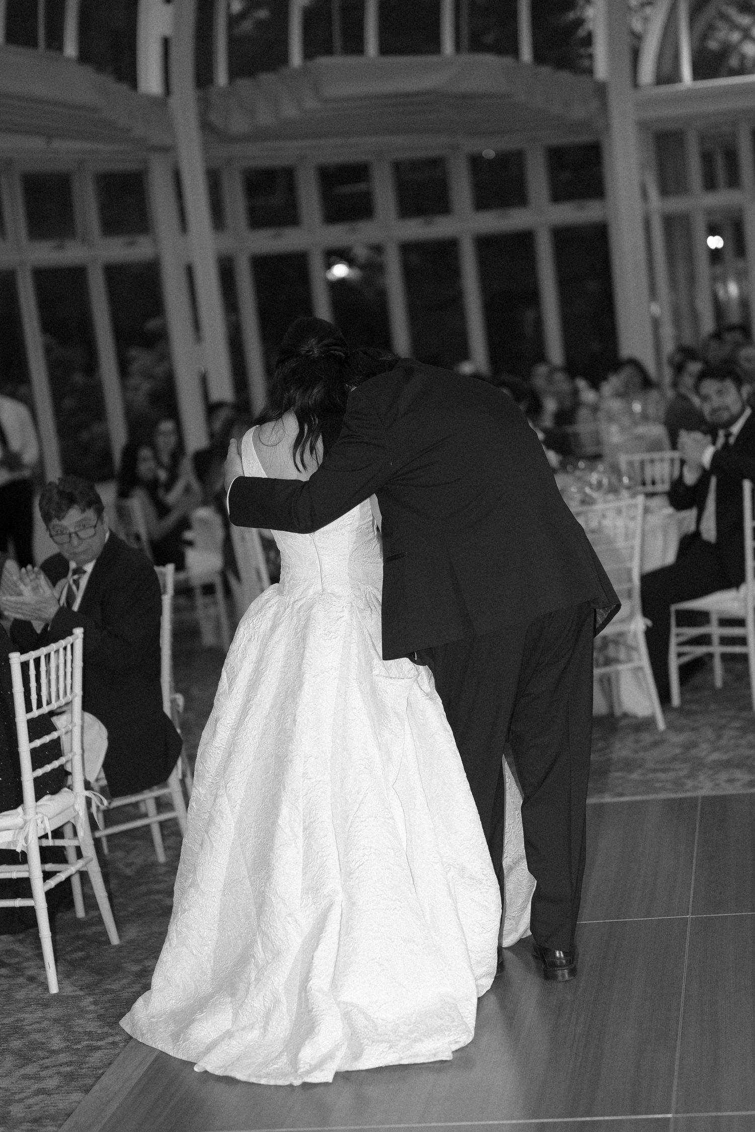 Black and white photo of bride and groom sharing first dance at elegant wedding reception.