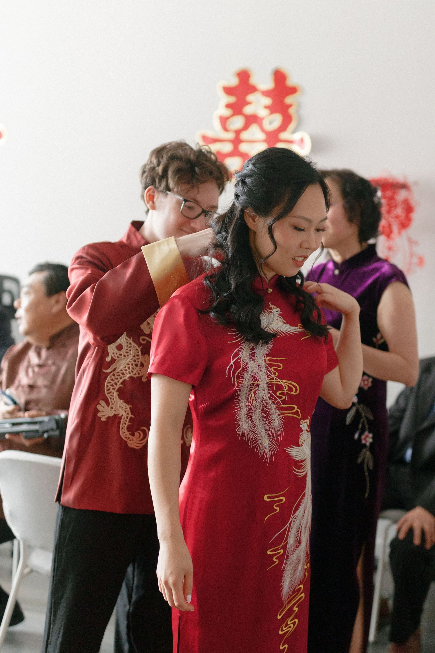 Couple in matching red dragon embroidered qipao outfits during a traditional Chinese wedding ceremony.