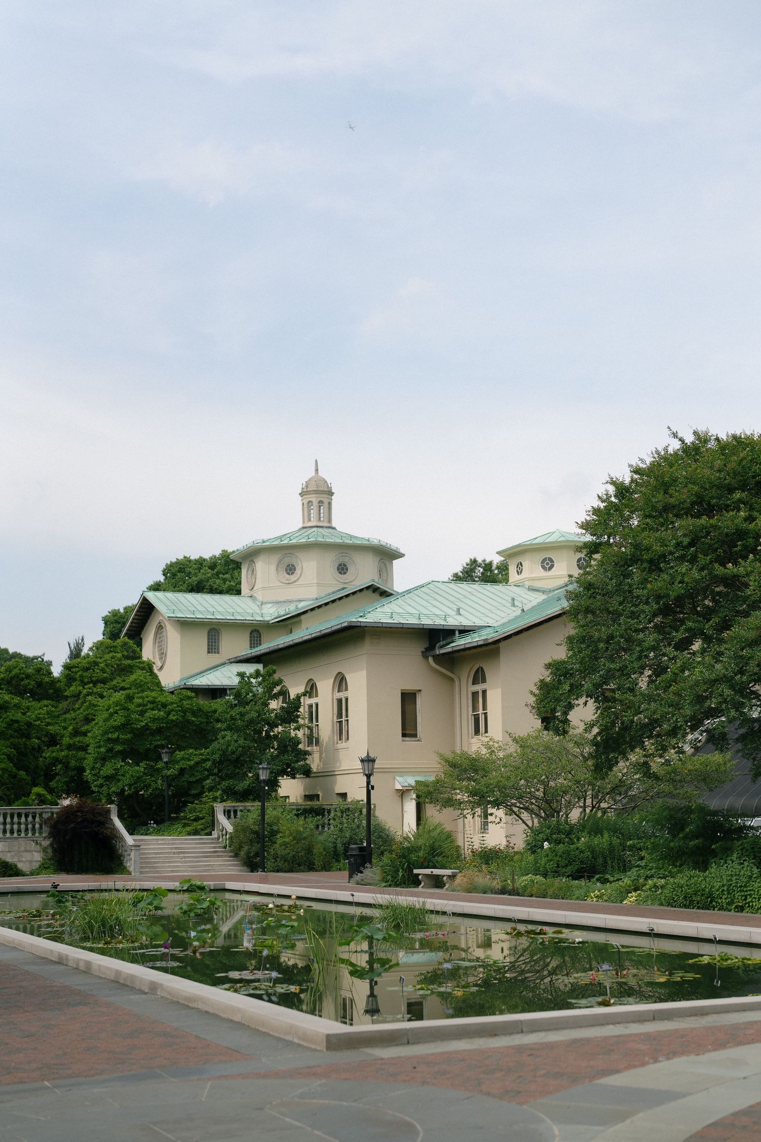 Elegant domed building with green roof reflected in lily pond.