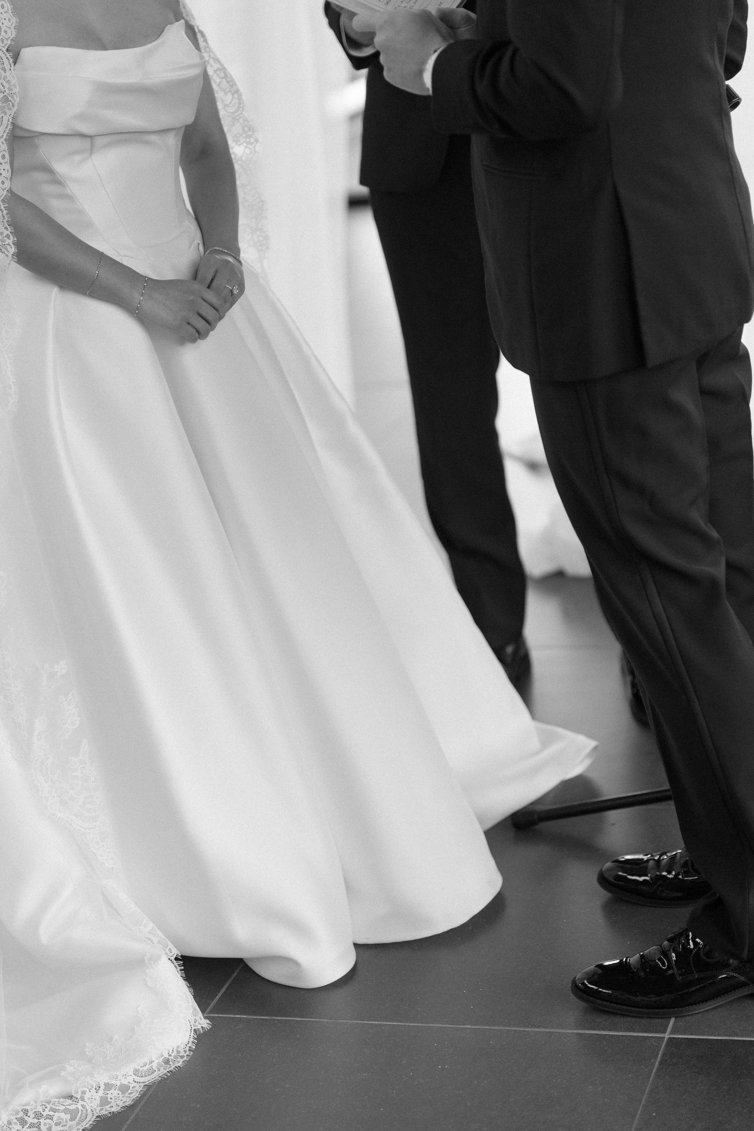 Black and white photo of bride and groom exchanging vows at wedding ceremony altar.