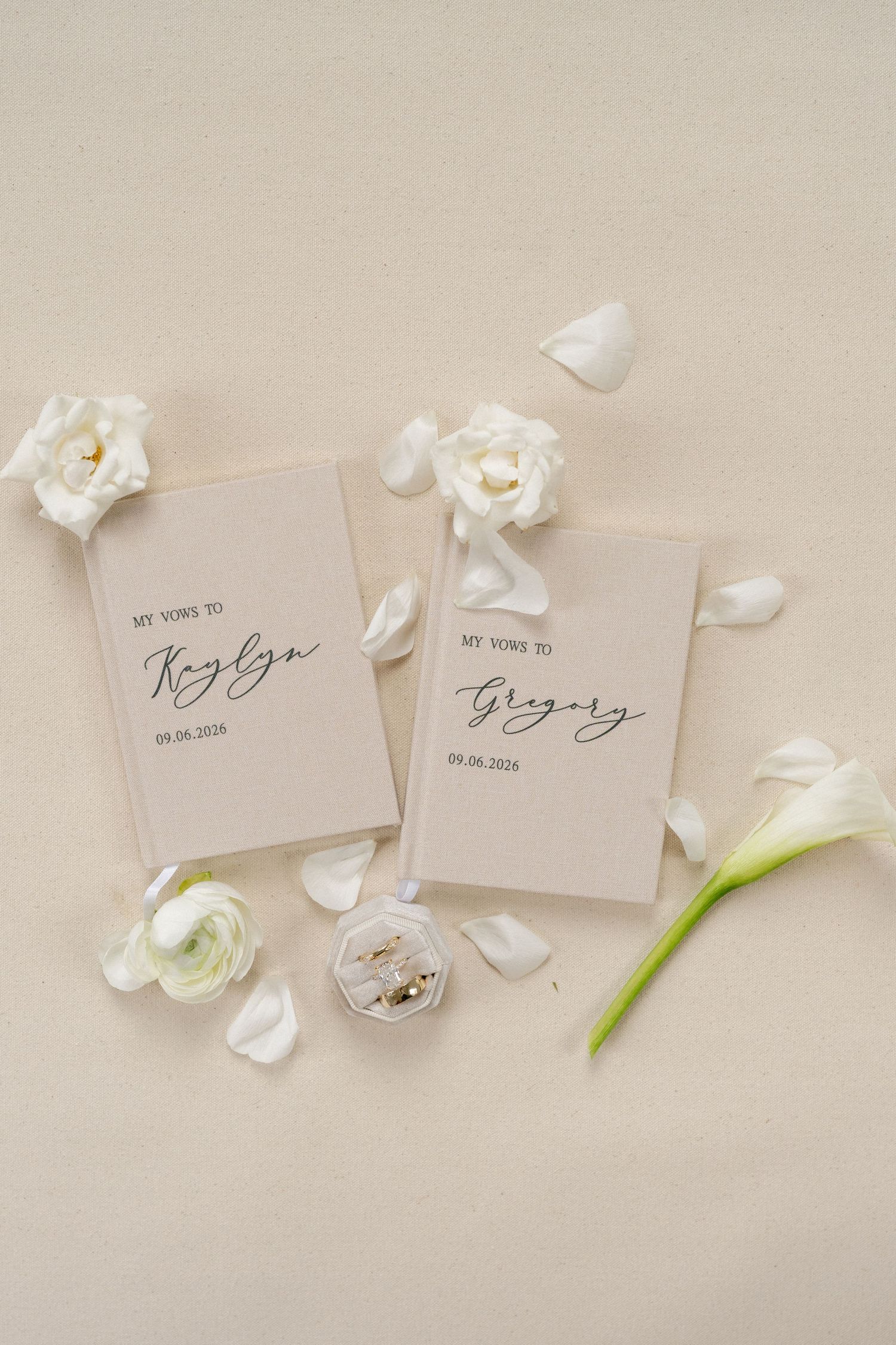 Elegant wedding vow booklets for Kaylyn and Gregory dated 09.06.2024, surrounded by white roses and petals on beige background.