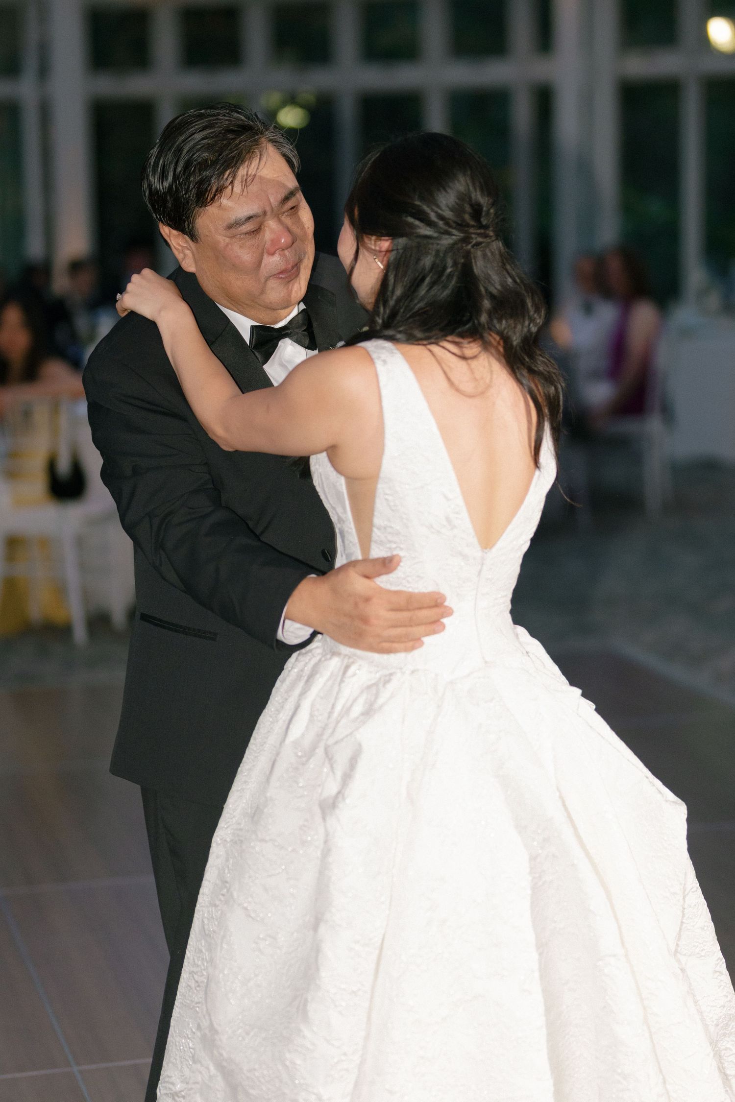 Father and bride share an emotional first dance at elegant wedding reception.