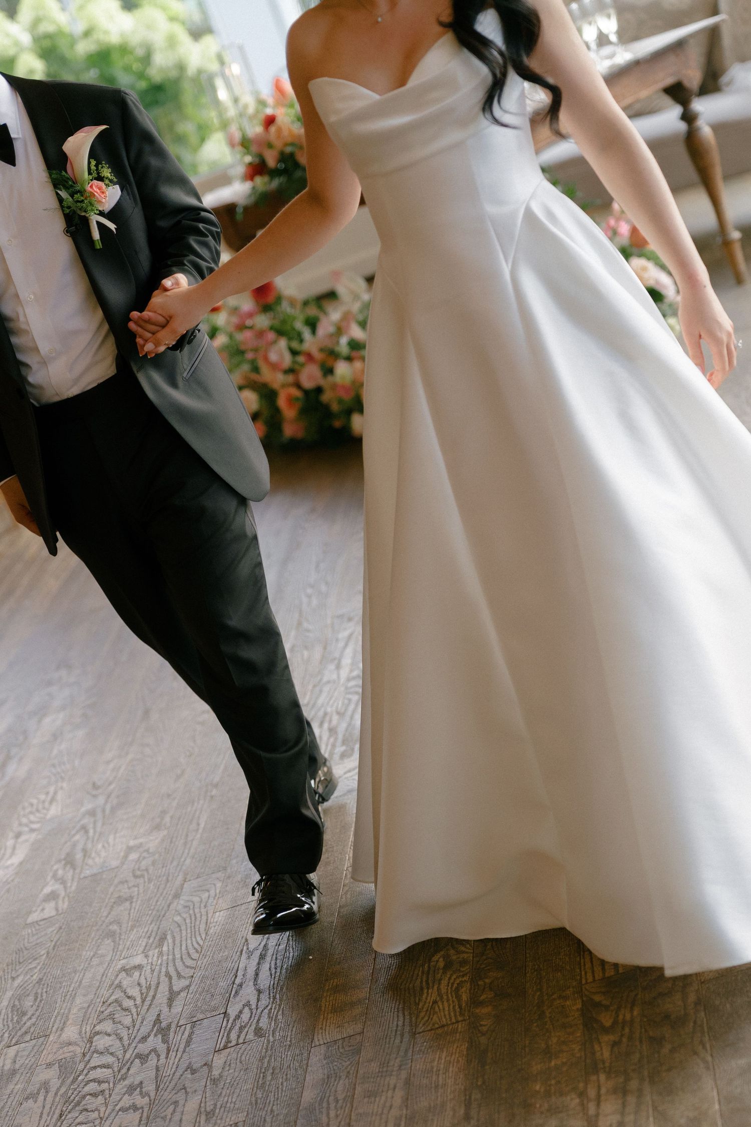 Bride in strapless white ball gown and groom in black suit share first dance.