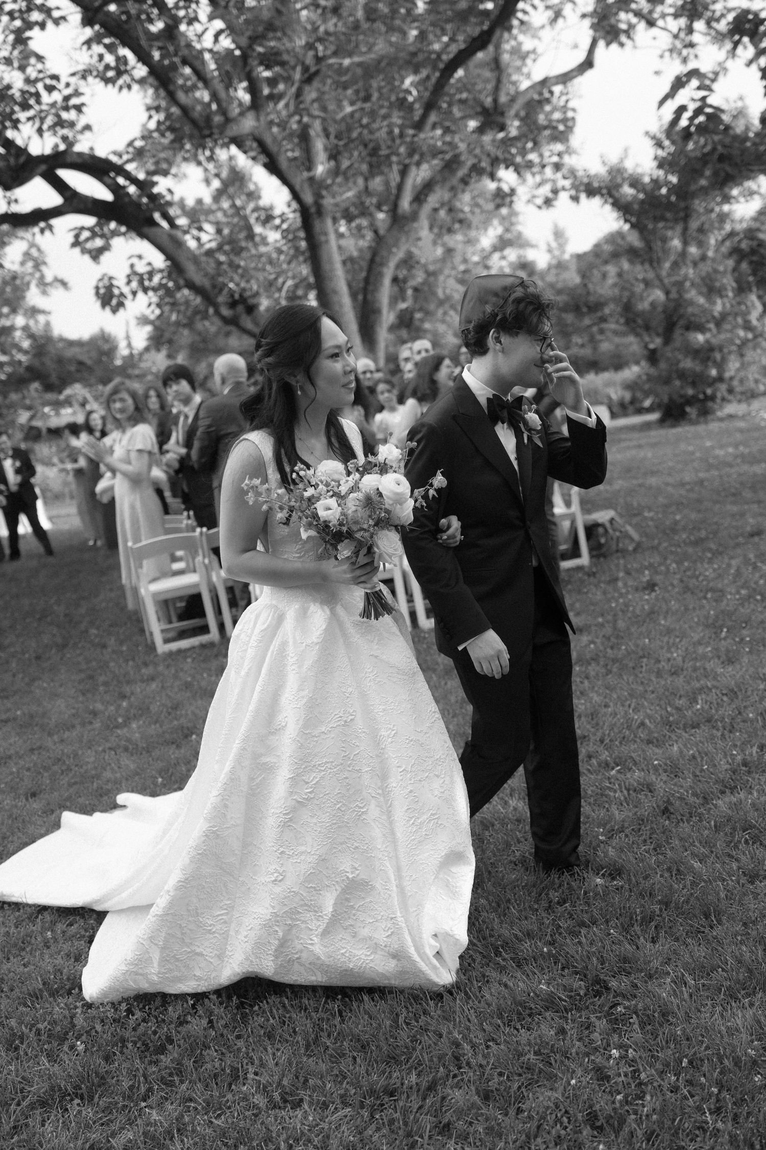 Bride and groom walking down the aisle after wedding ceremony in black and white photo.