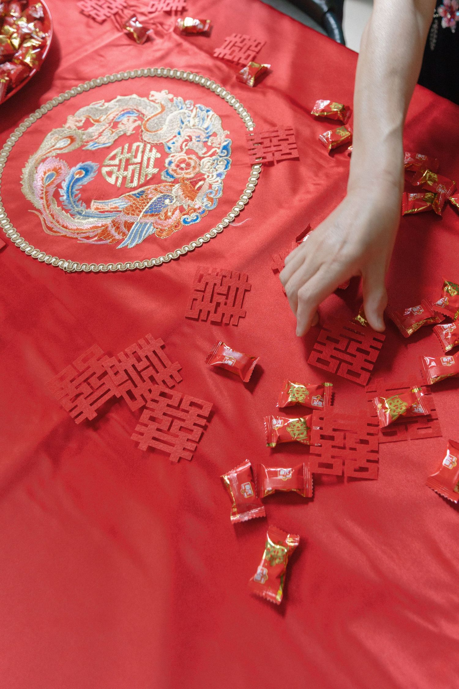 Traditional Chinese wedding decorations with red double happiness symbols and gold candy on red fabric.
