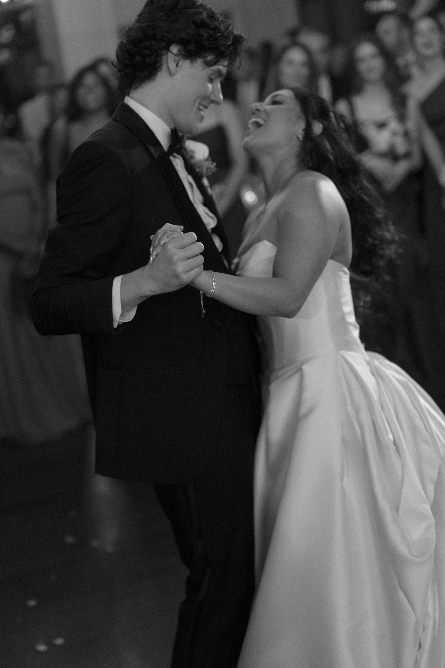 Bride and groom share romantic first dance in black and white photo at elegant wedding reception.