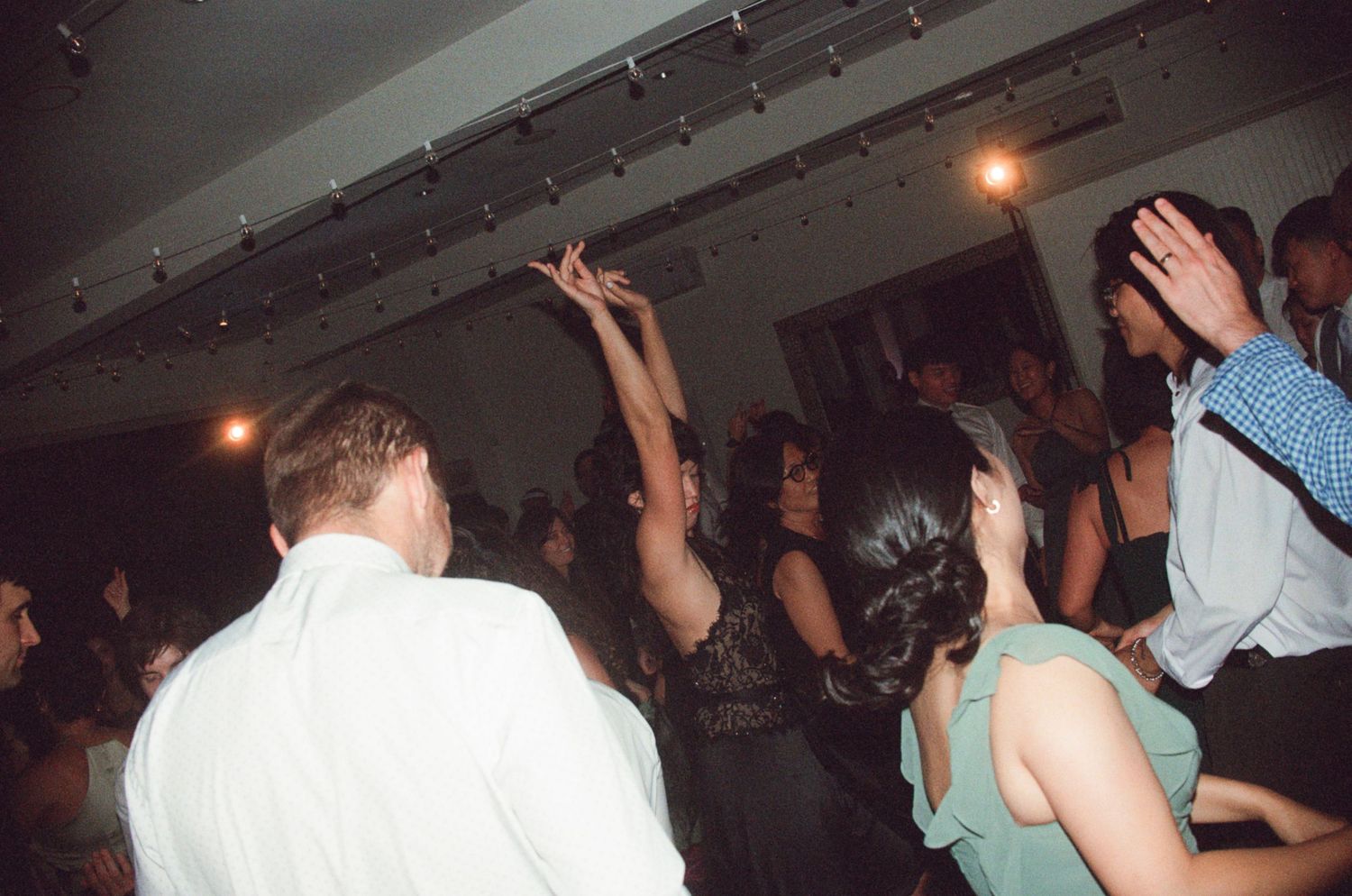 Guests dancing energetically at a lively wedding reception party on a crowded dance floor.