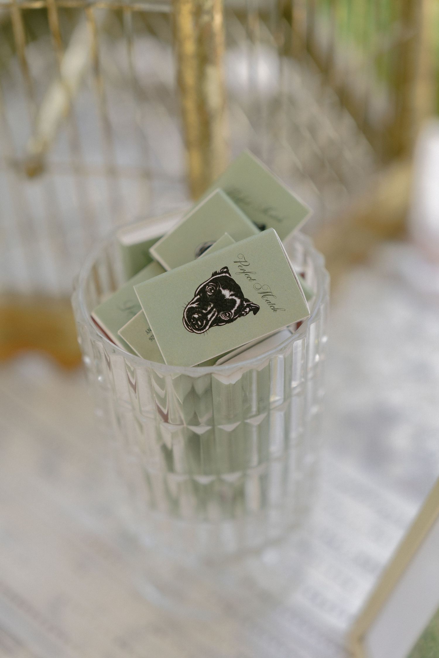 Green custom matchbooks with monogram logo displayed in a crystal glass at a wedding reception.