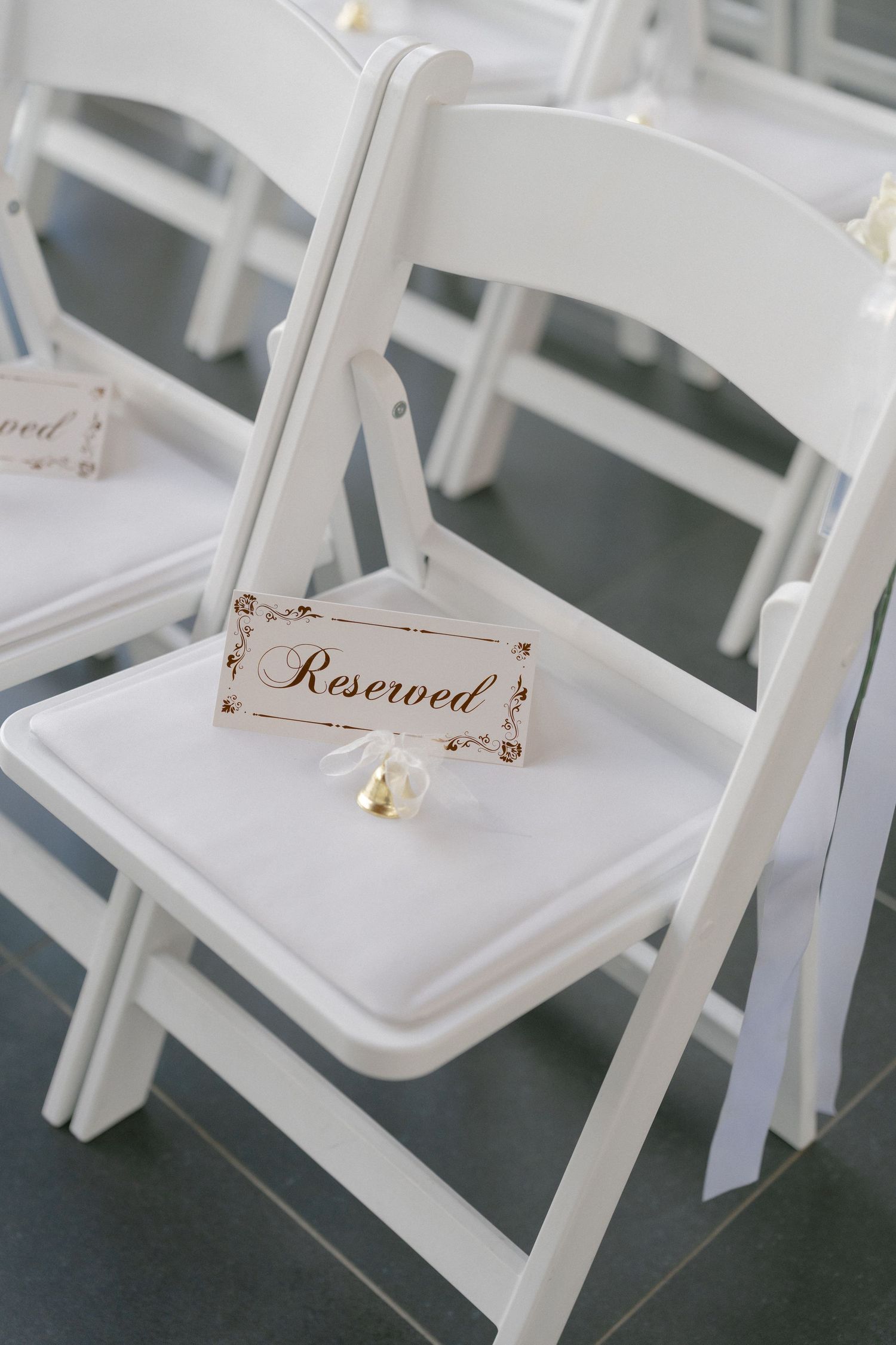 White folding chair with elegant Reserved sign at a wedding ceremony venue.