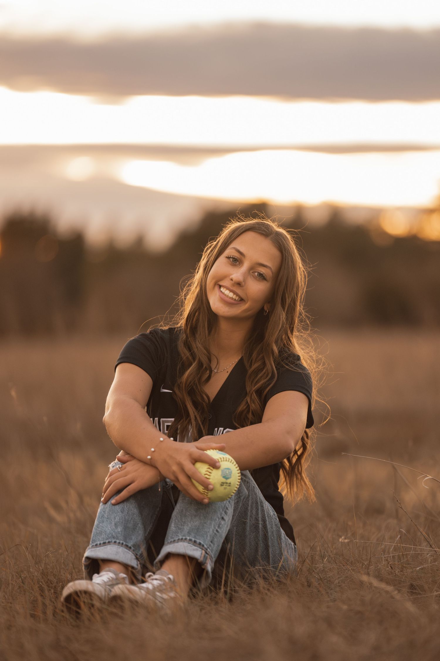 Person sits in golden field during sunset photoshoot.