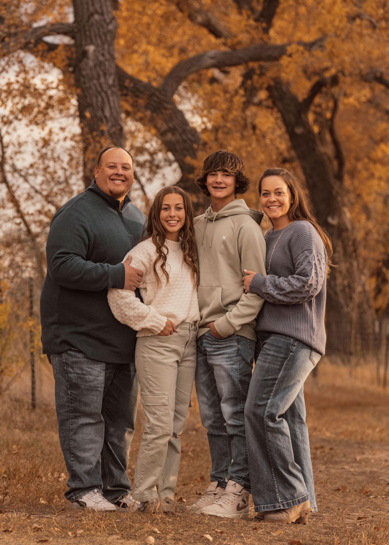 Family group sharing joyful moments outdoors in a fall setting with warm lighting.