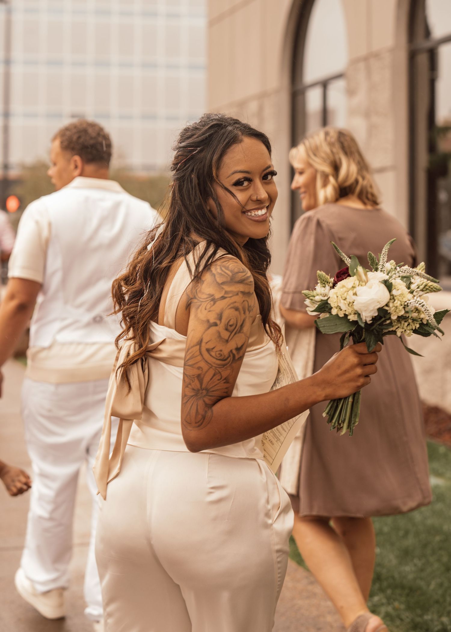 Bride in white dress holding bouquet during outdoor wedding celebration.