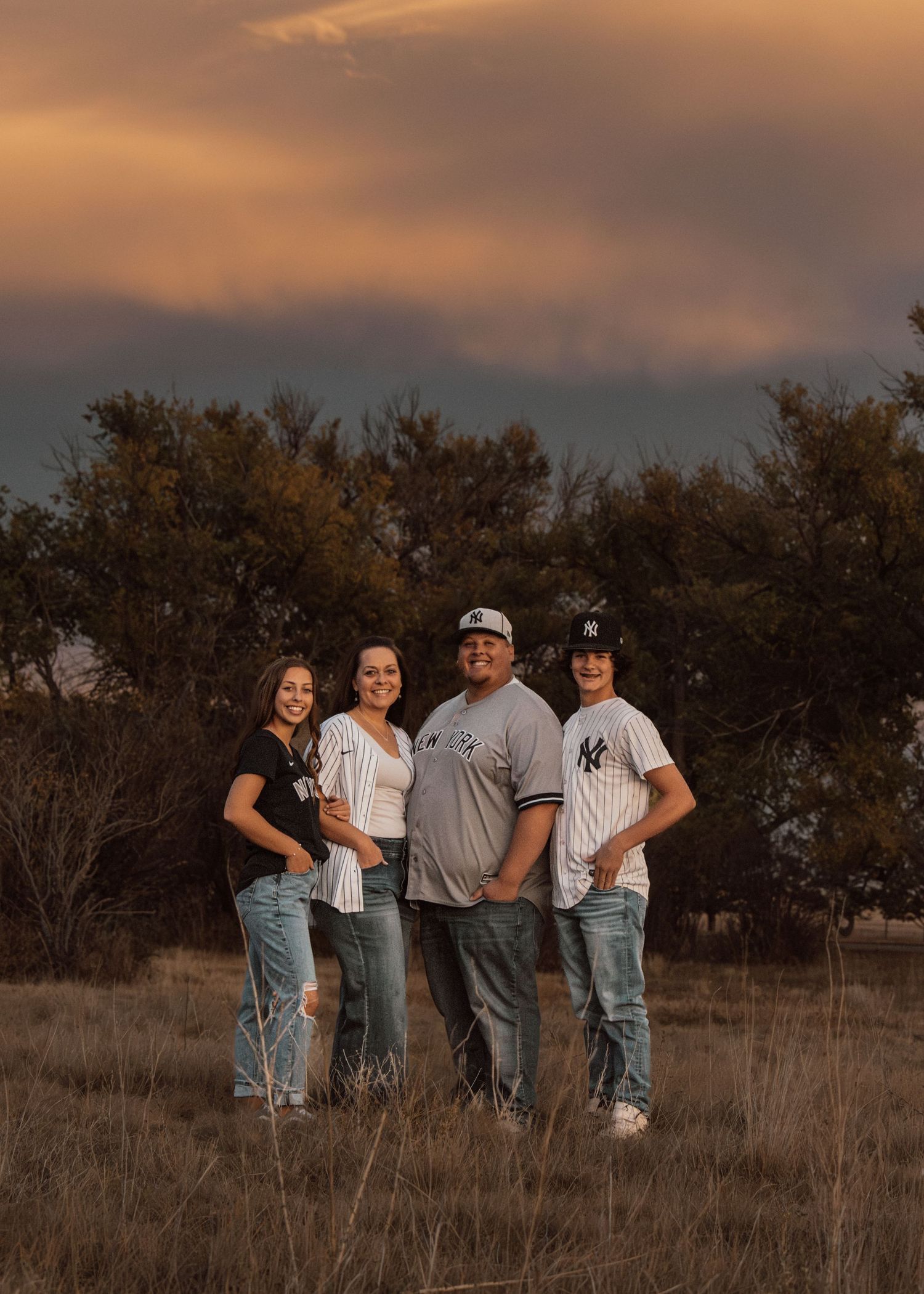 Group photo session at sunset in a rustic field with casual denim outfits.