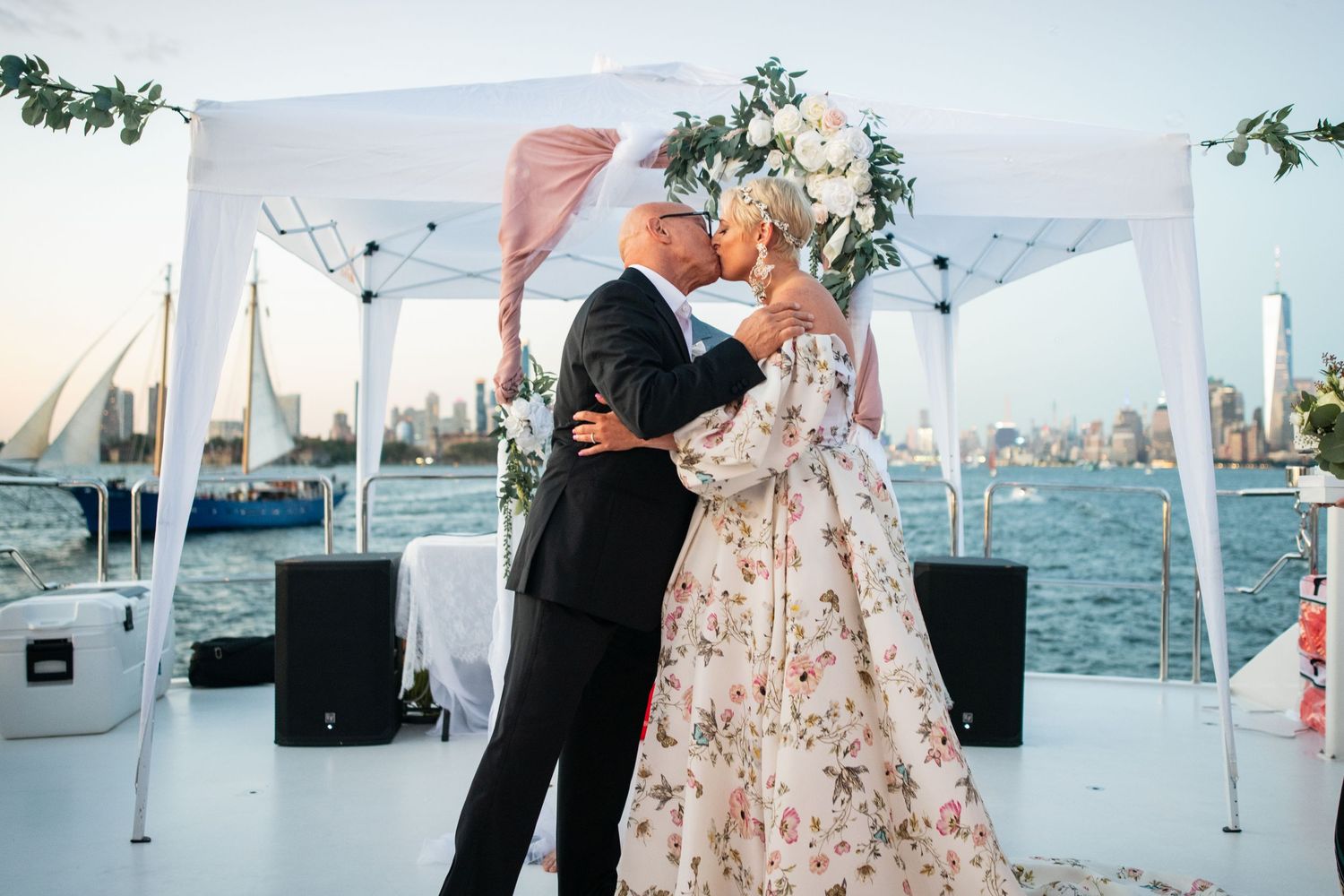 Couple shares their first dance under white tent on waterfront deck.