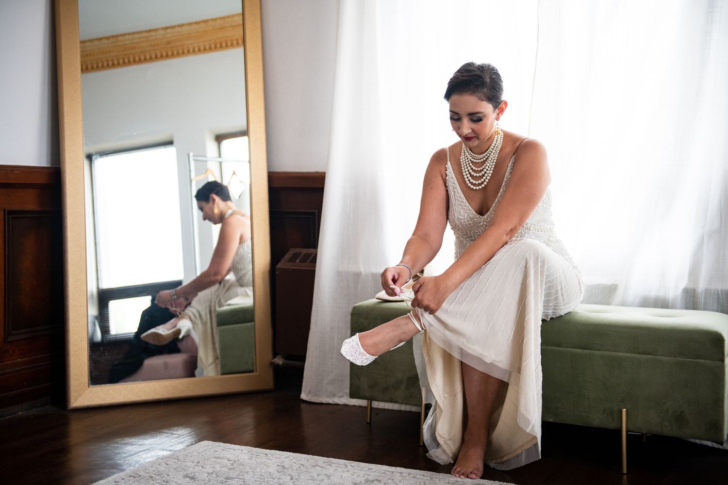 Wedding preparations in a room with a vintage mirror and green velvet couch.