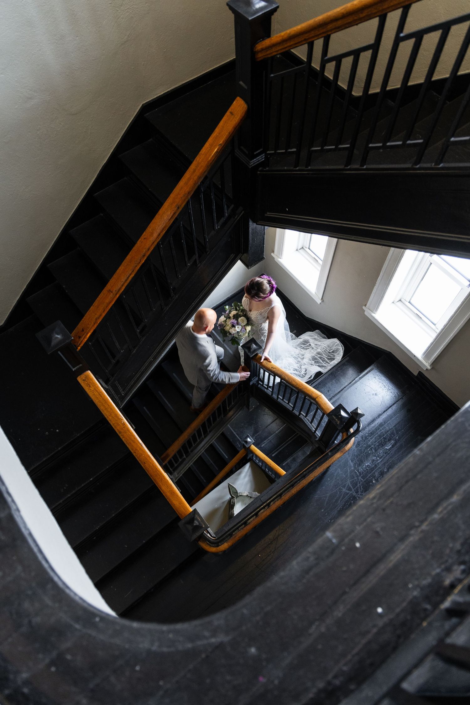 An aerial view looking down a spiral staircase with a couple posing on the steps.