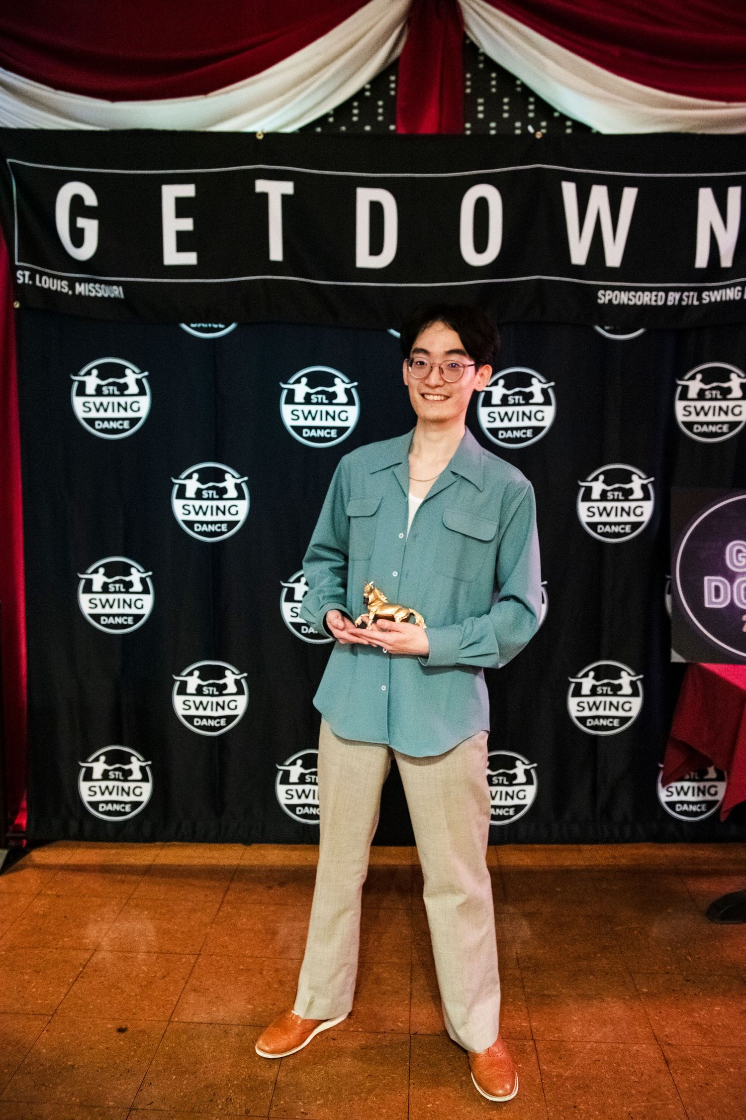 Person standing in front of a 'GET DOWN' backdrop banner at a dance event.