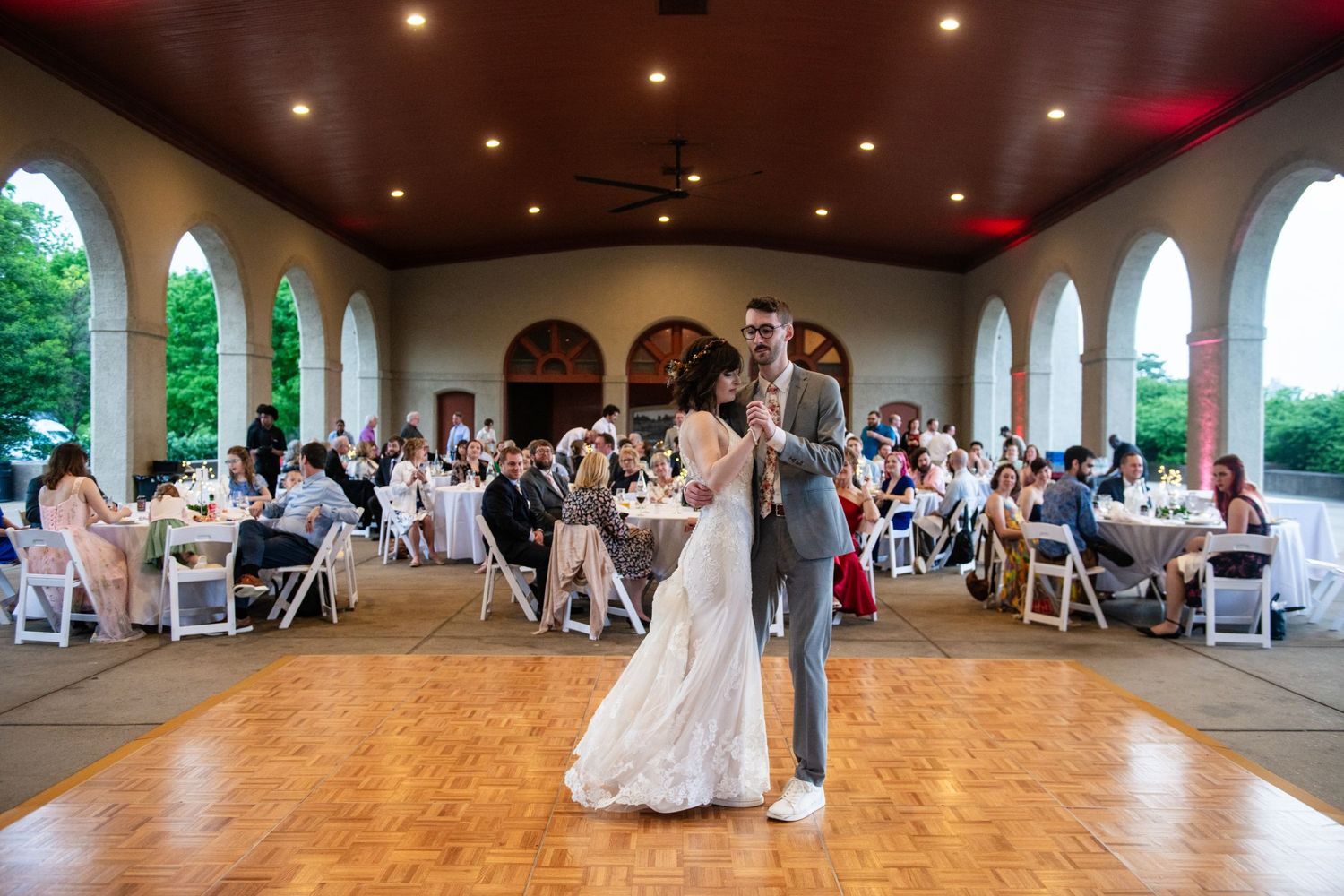 Wedding reception venue with arched windows and guests seated at tables watching the dance floor.