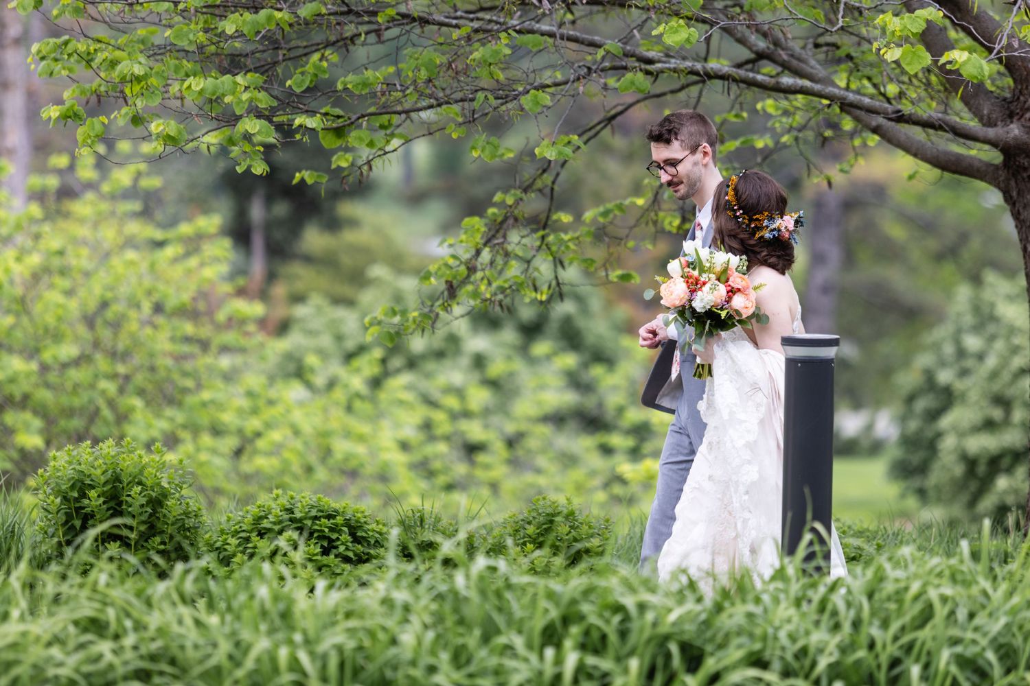 Wedding couple sharing intimate moment in lush garden setting with spring foliage.