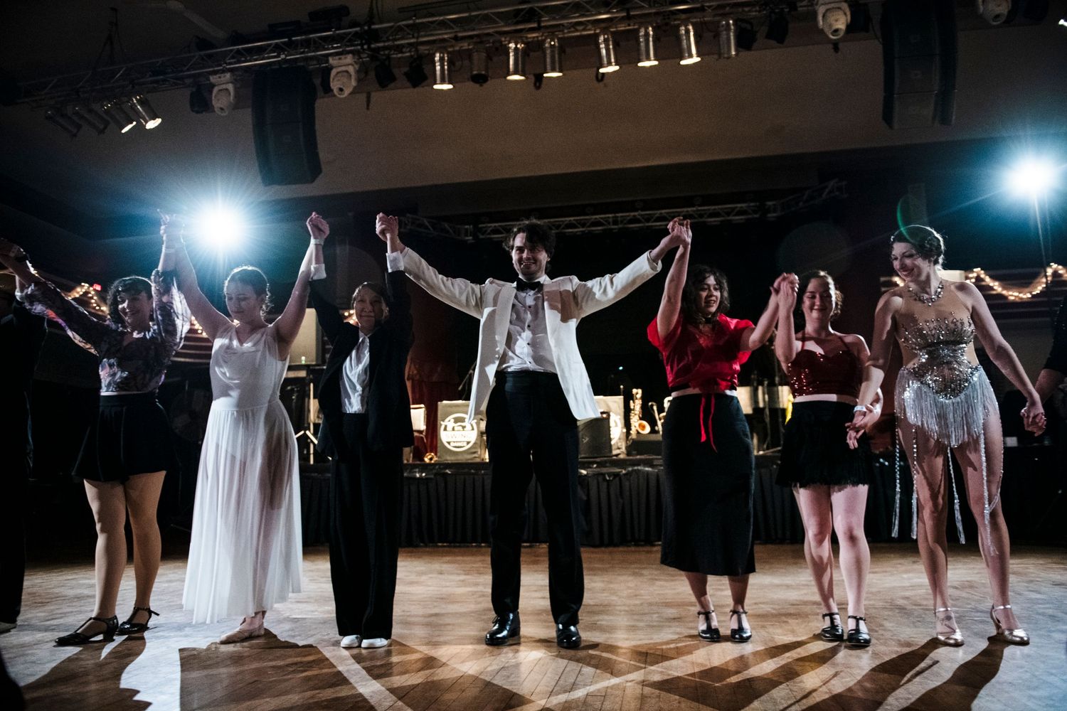 Performers celebrating on stage with arms raised during a show finale.