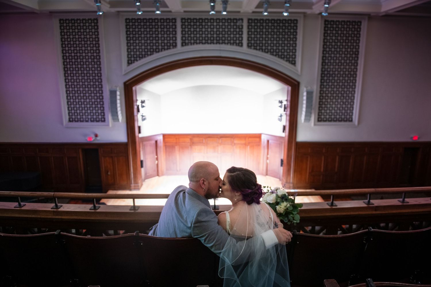 A couple sharing an intimate moment in theater balcony seating.