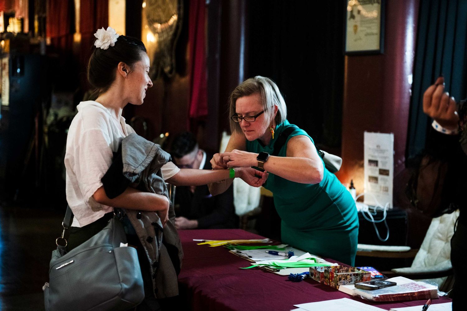 Person in green apron assisting at an event registration or check-in table.