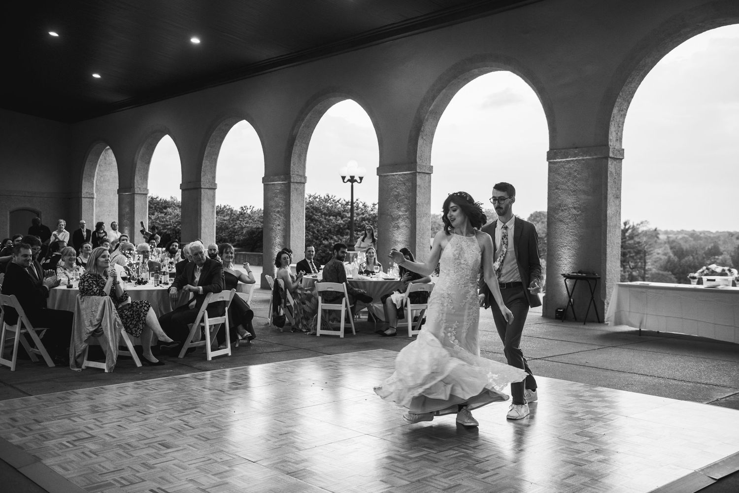 Black and white capture of an intimate wedding dance moment in a grand reception venue.