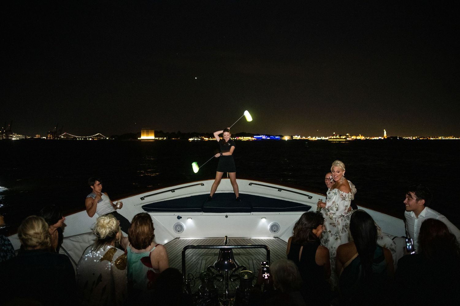 Nighttime celebration on a boat deck with city lights twinkling in the background.