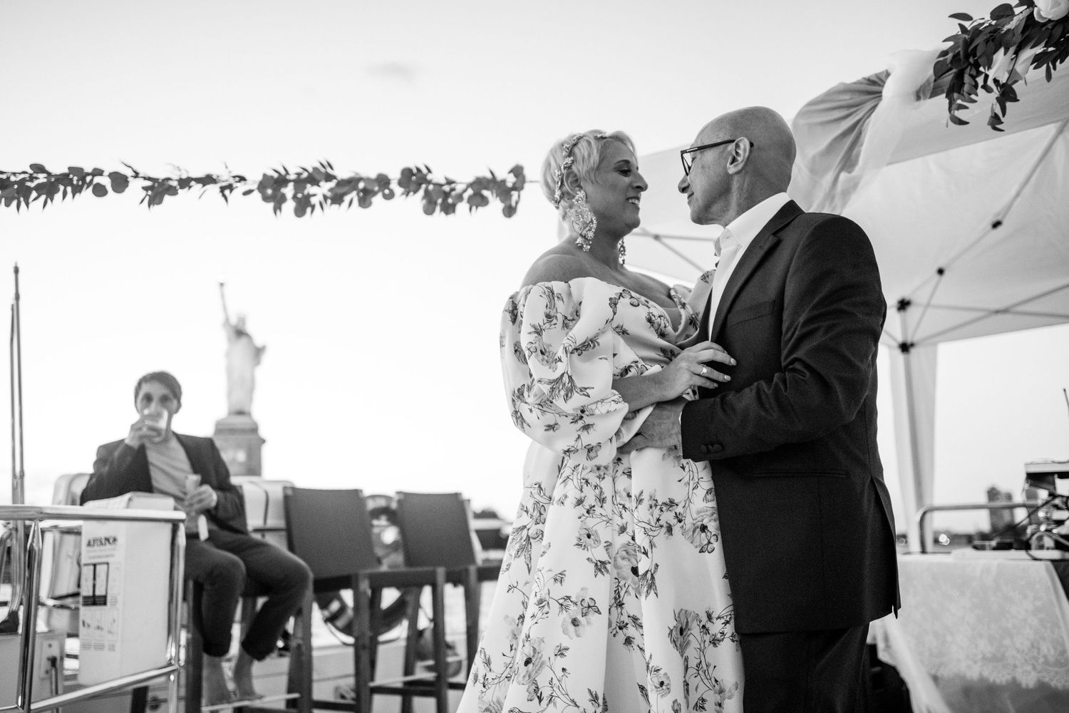 Black and white portrait of couple dancing at waterfront wedding venue.