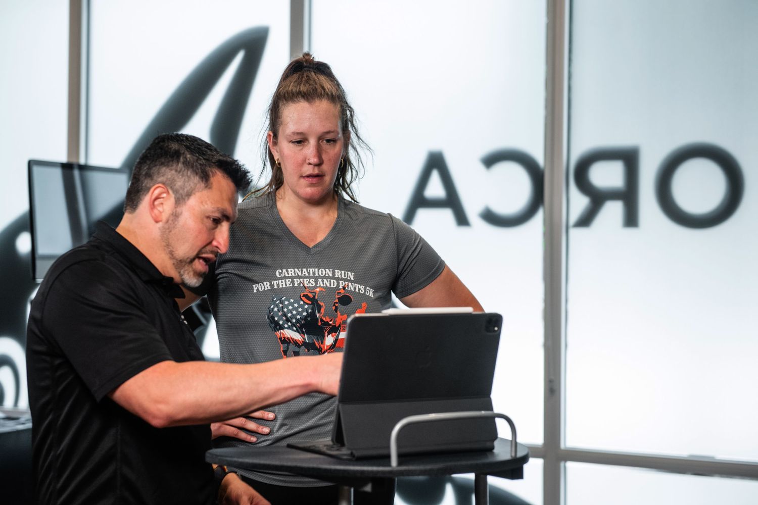 Training consultation session with laptop computer in modern fitness facility.