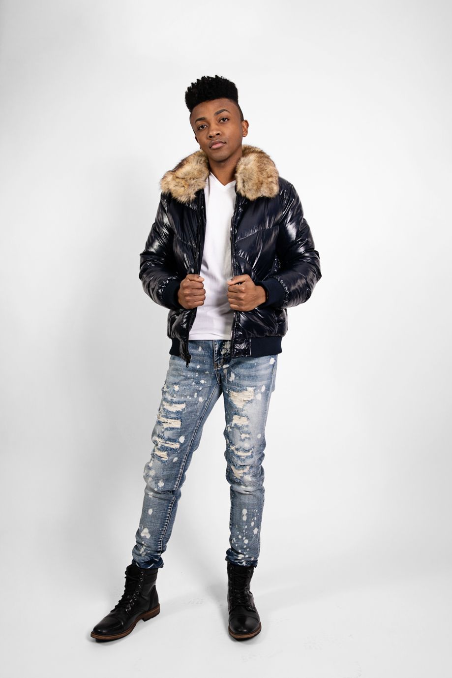 Urban style with leather jacket, fur collar, distressed jeans and boots against white background.