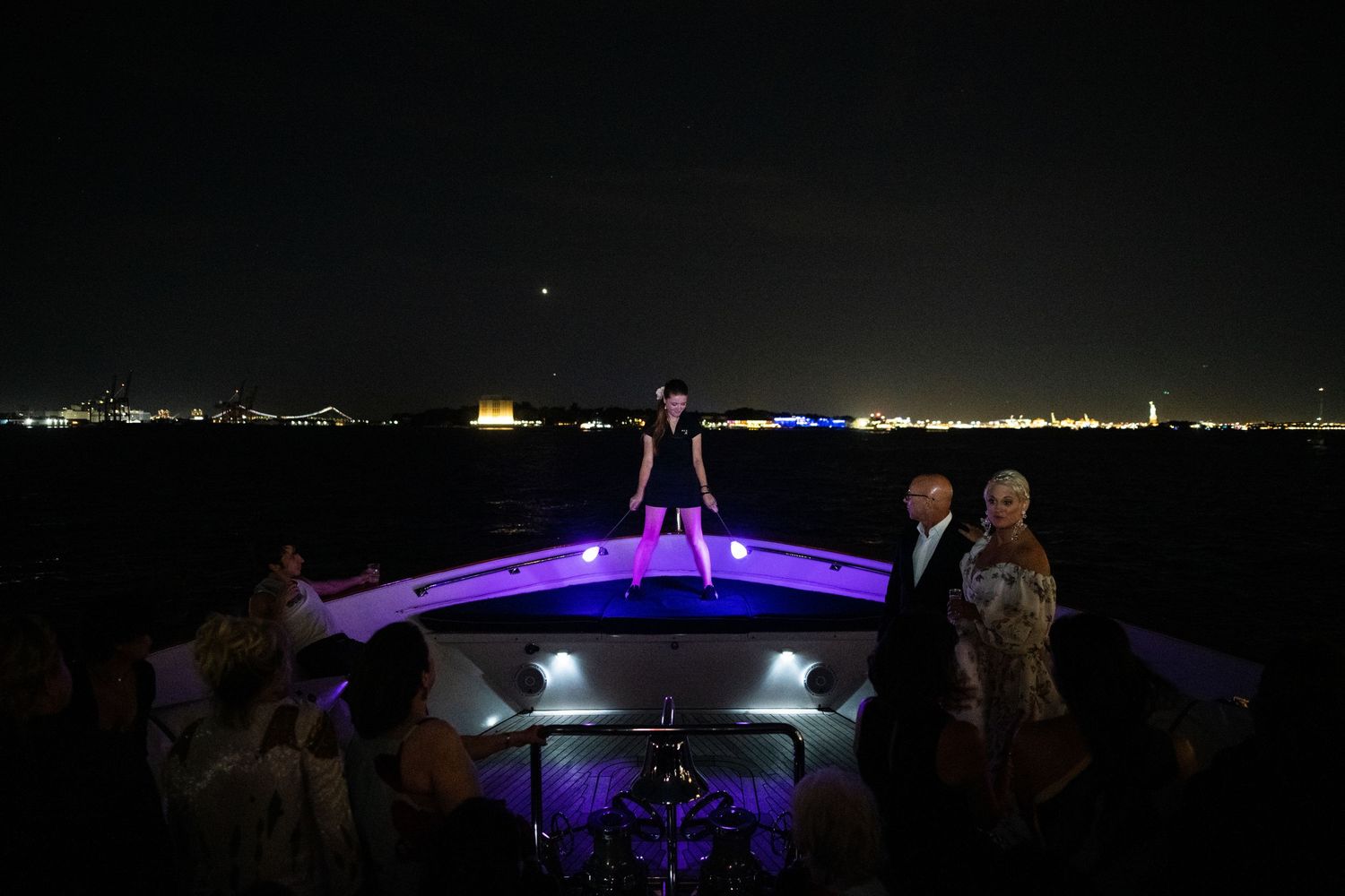 Silhouettes of people standing on illuminated boat deck at night.