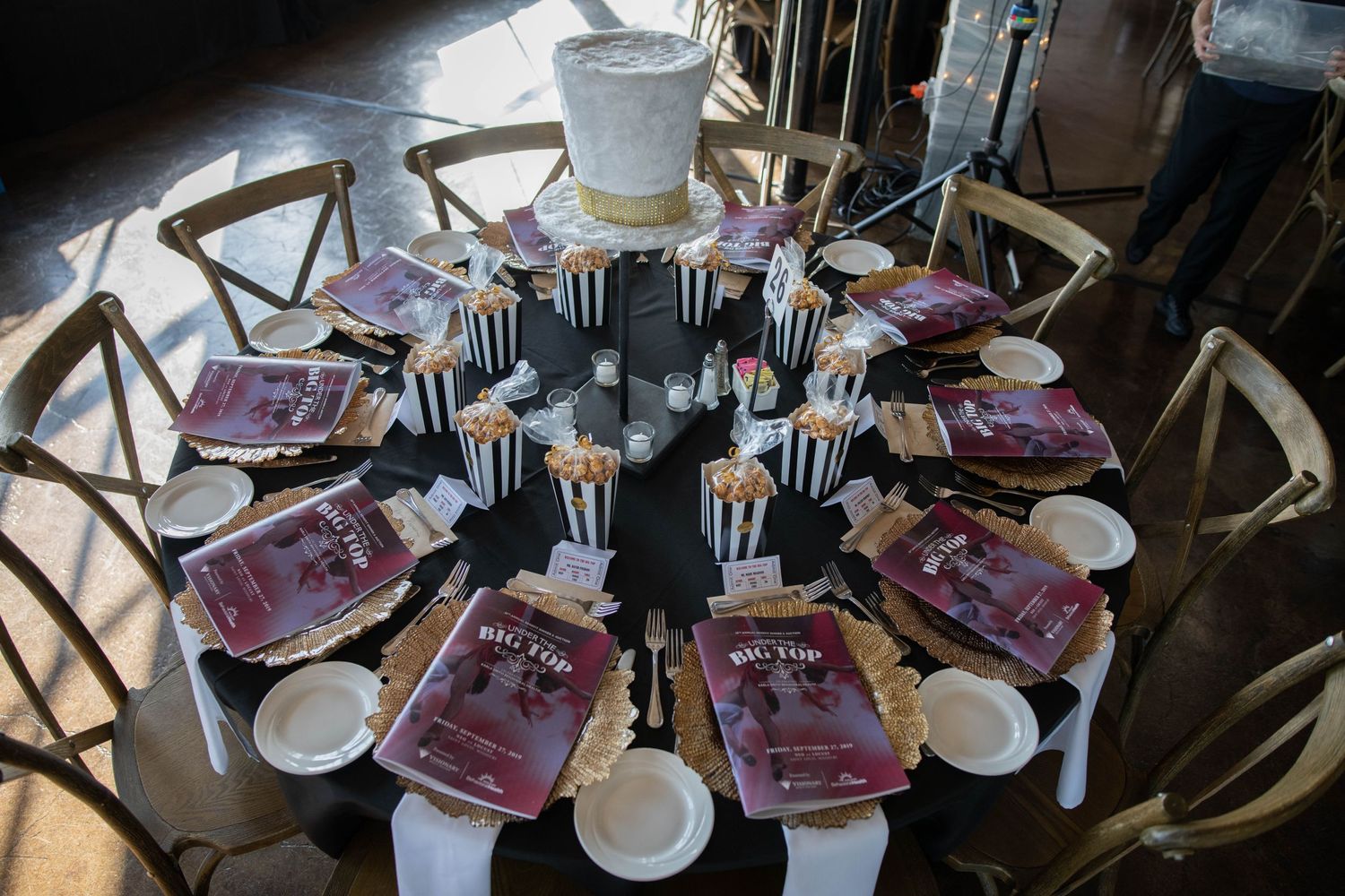 Circular table setting with black and white striped decor and Big Top themed event programs.