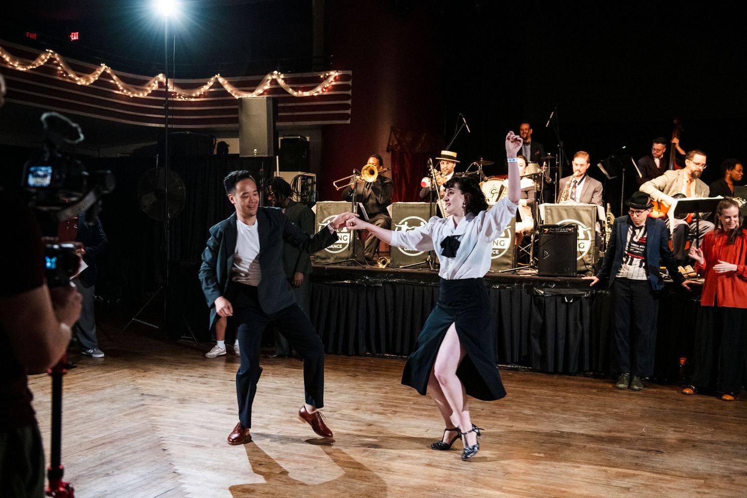 Dance party scene with string lights and live band performing on stage.