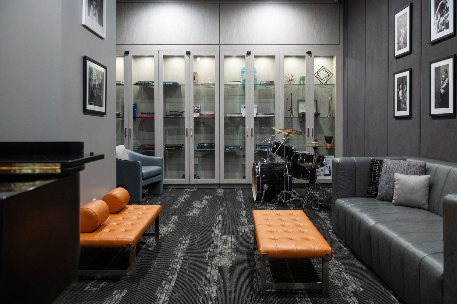 Music room with glass display cases, orange leather benches, and dark flooring.