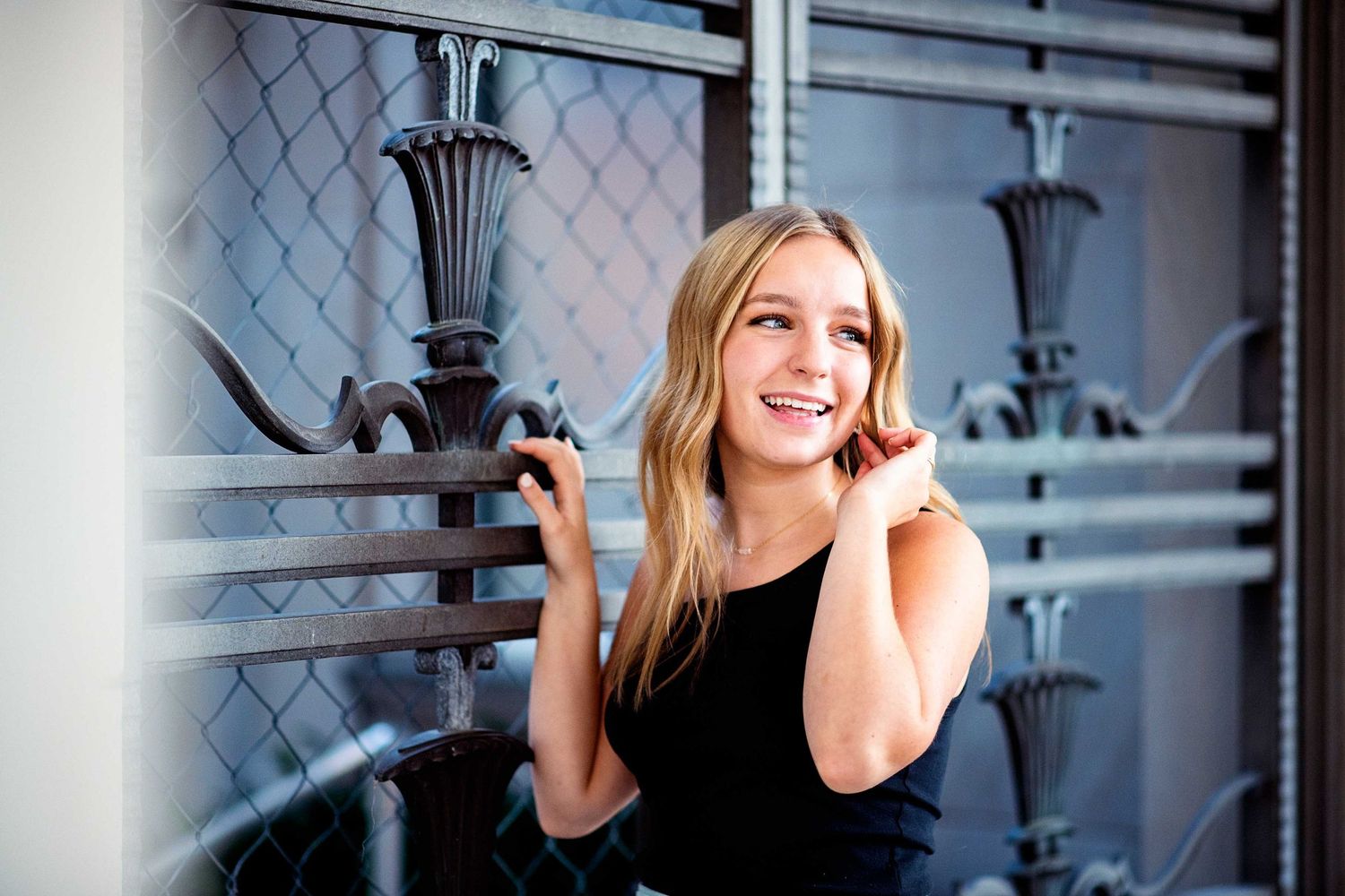 A set of black and white portrait photos showing someone smiling and posing against a textured mesh backdrop.